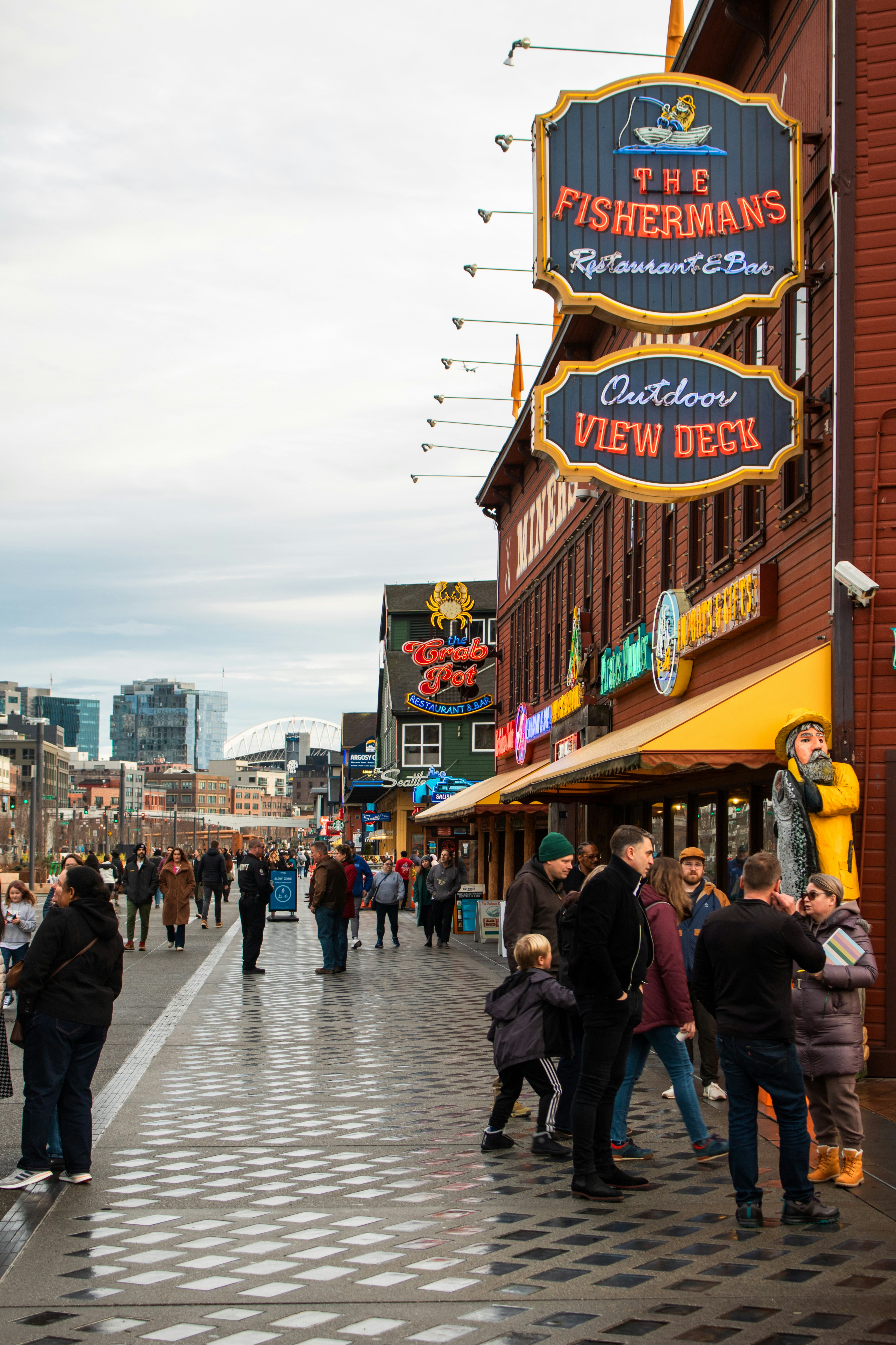 People walk by a waterfront restaurant and deck.