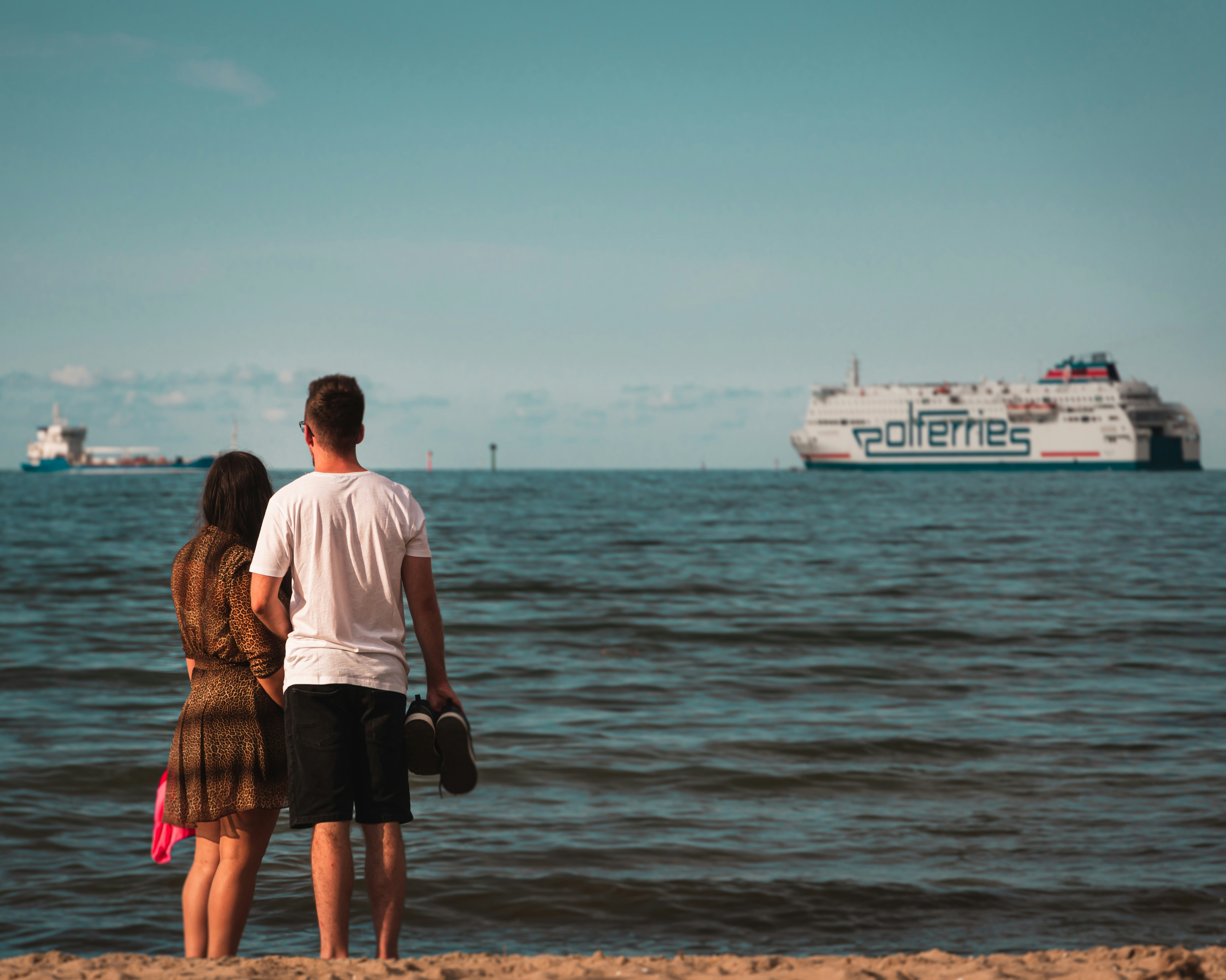 Couple watches ferries on the ocean.