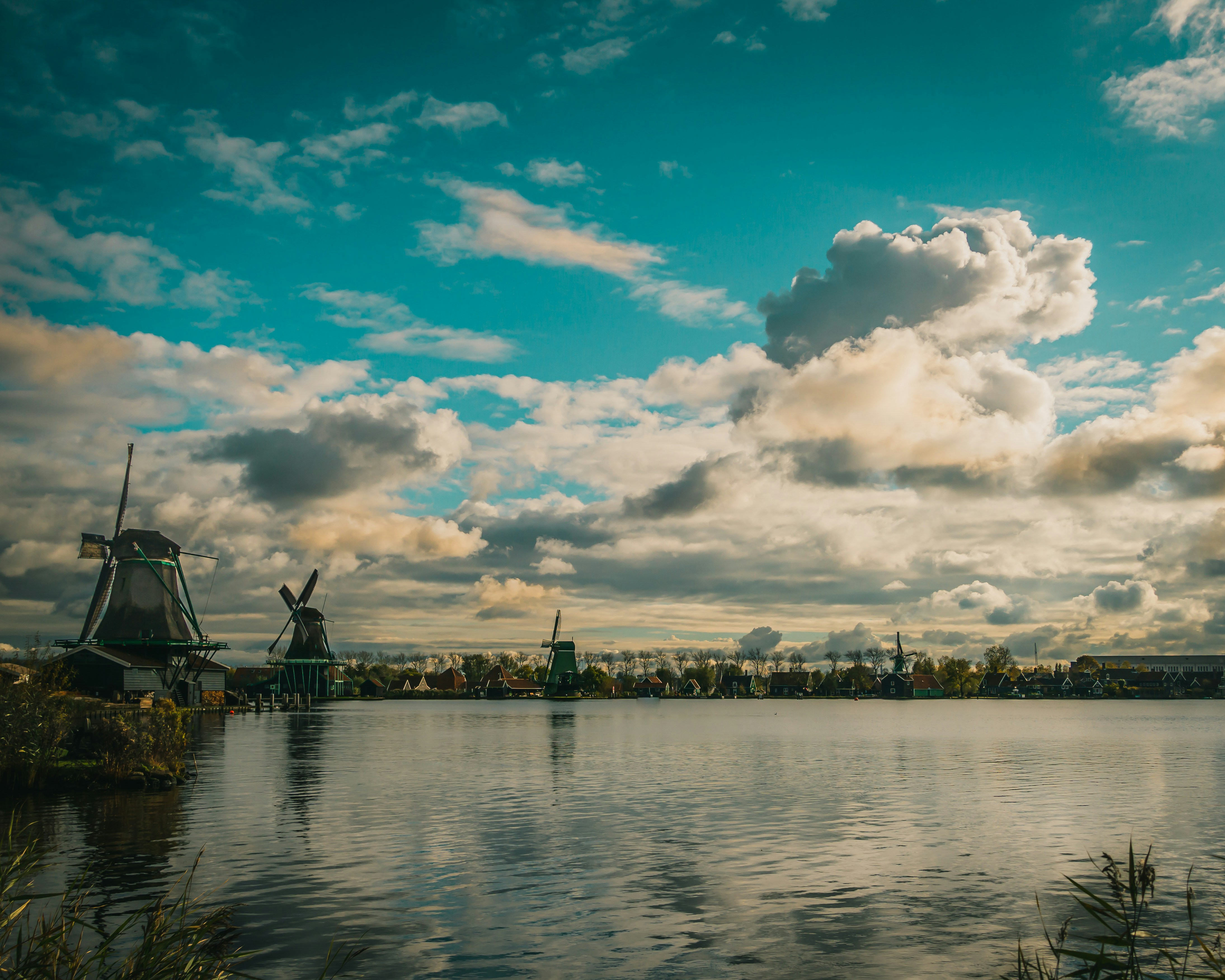 Windmills on a lake under a bright, cloudy sky.