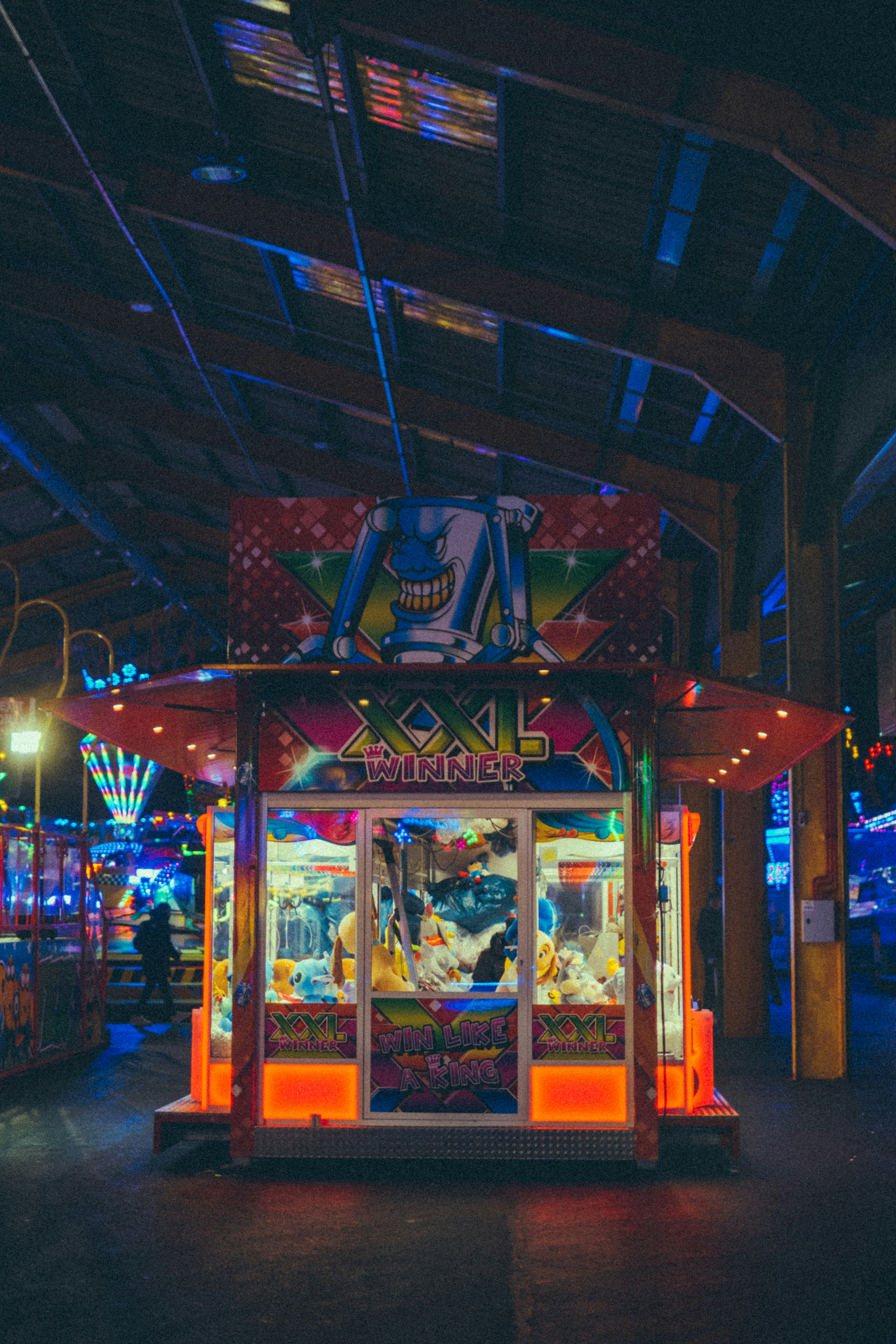 A brightly lit claw machine at a carnival.