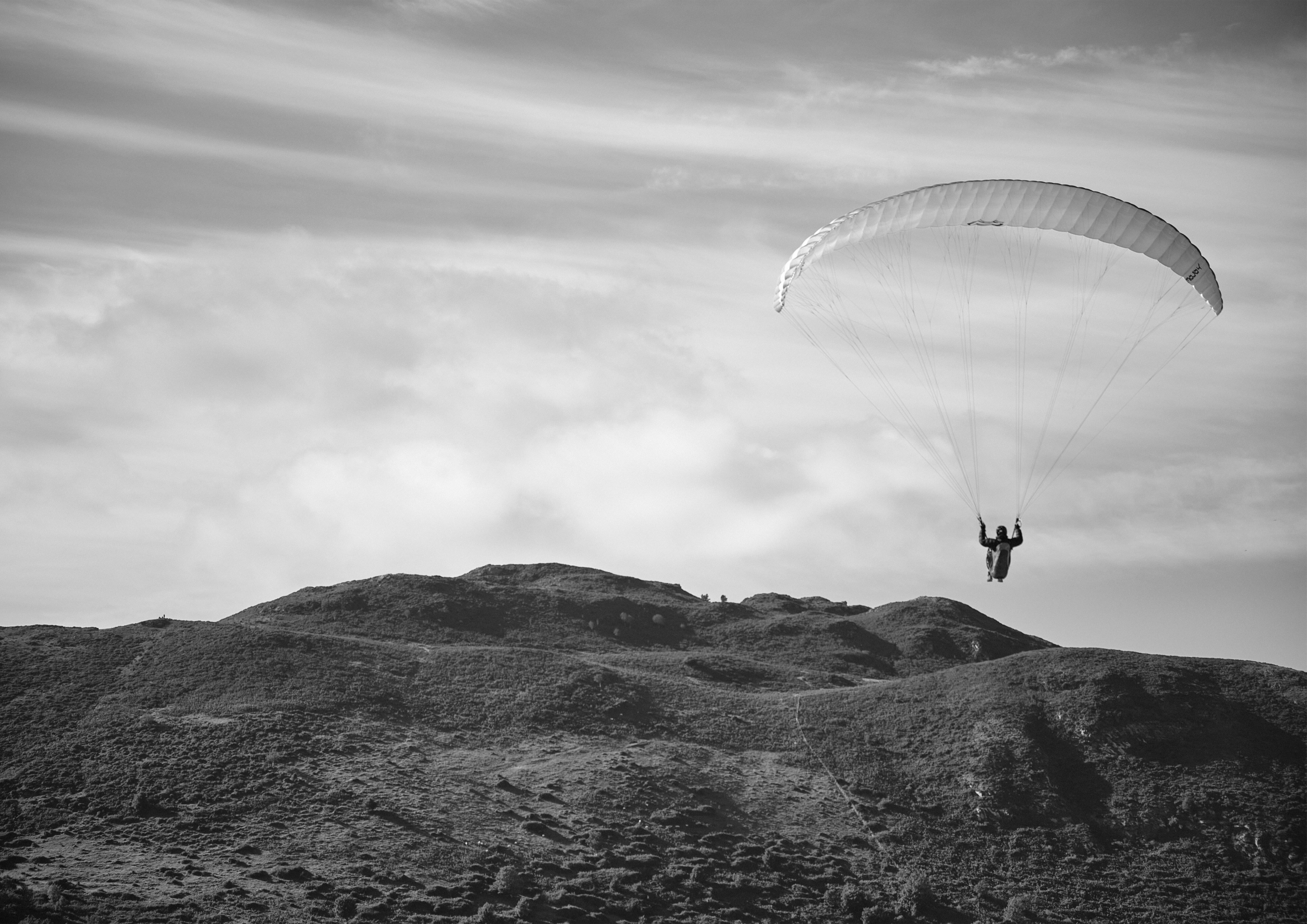 Ein Gleitschirm schwebt über einem sanften Hügel.