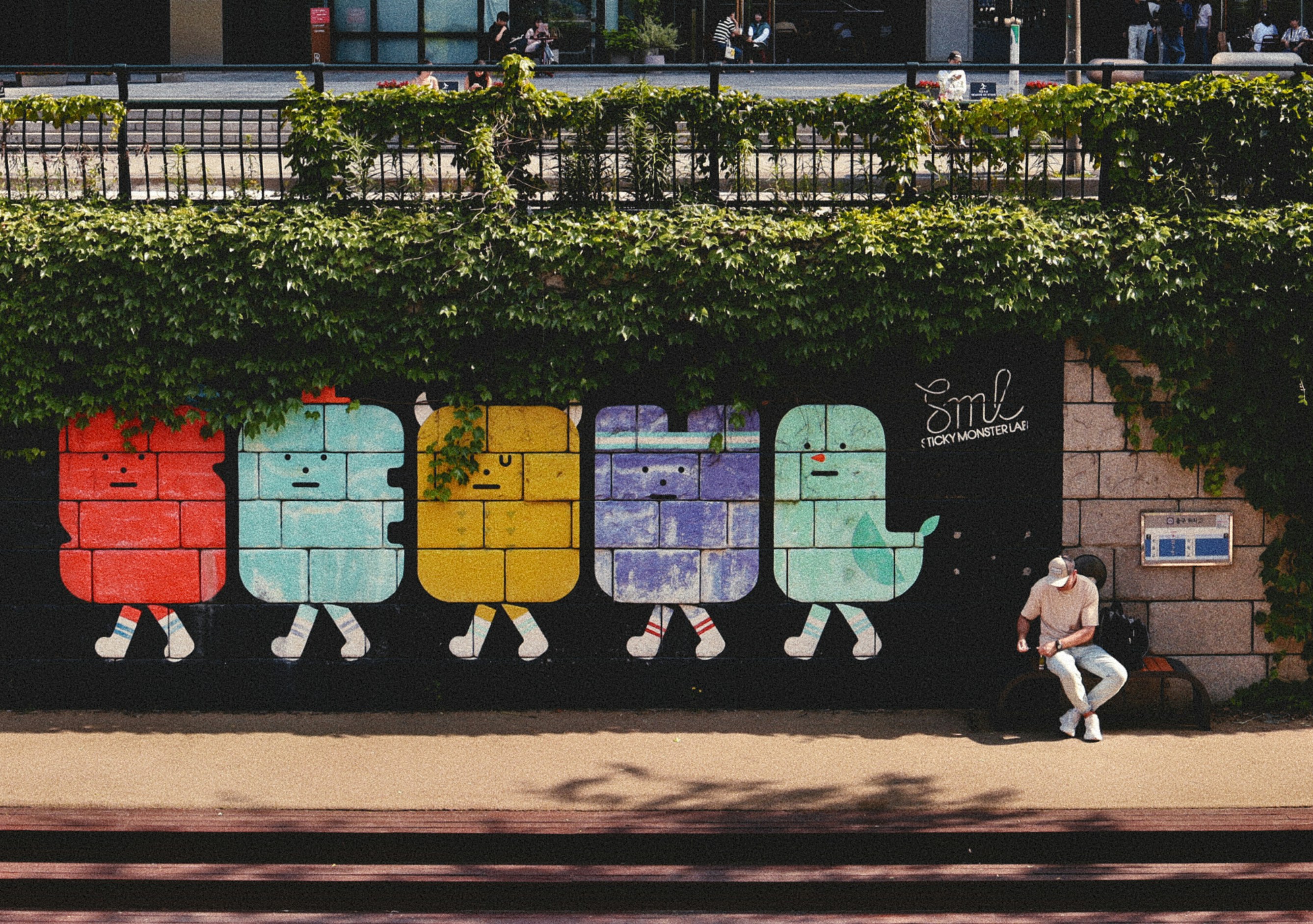 Colorful mural depicts walking characters near a seated person.
