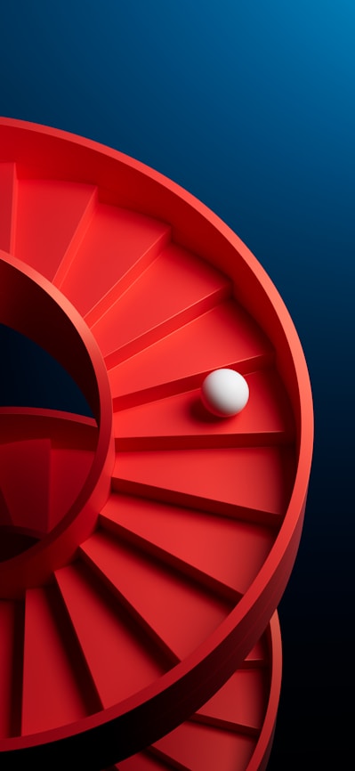A ball rolls down a red spiral staircase.