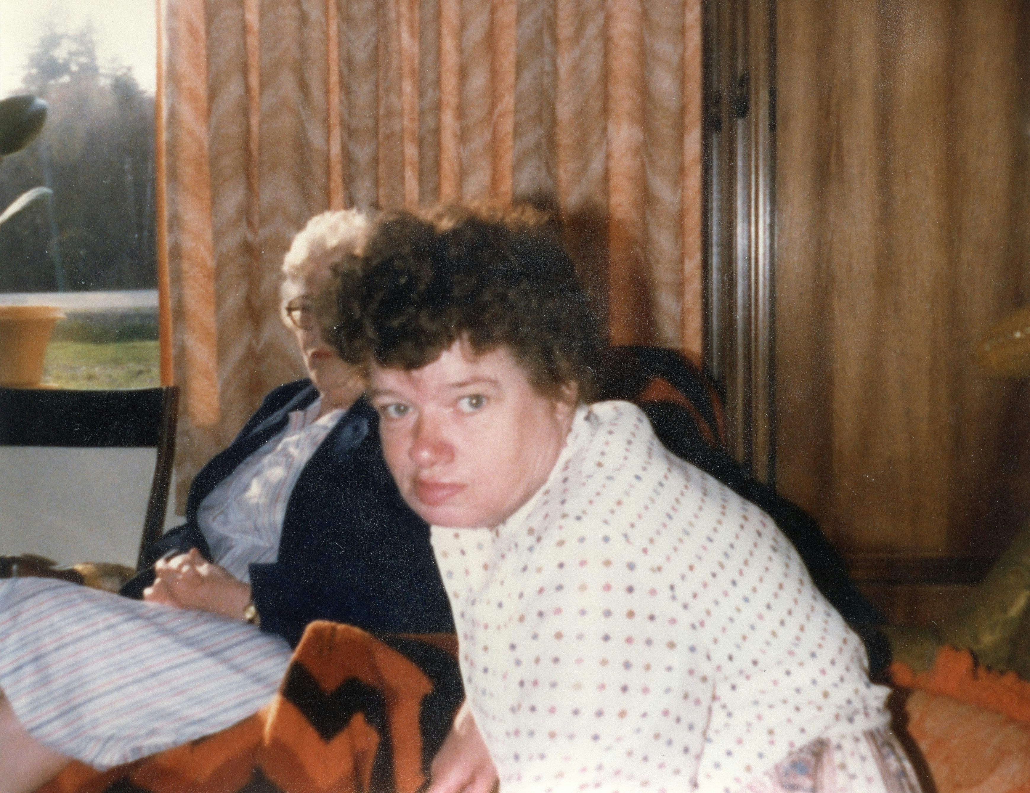 Two people sitting indoors near a window.
