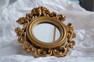 A gold-framed mirror on crinkled paper.