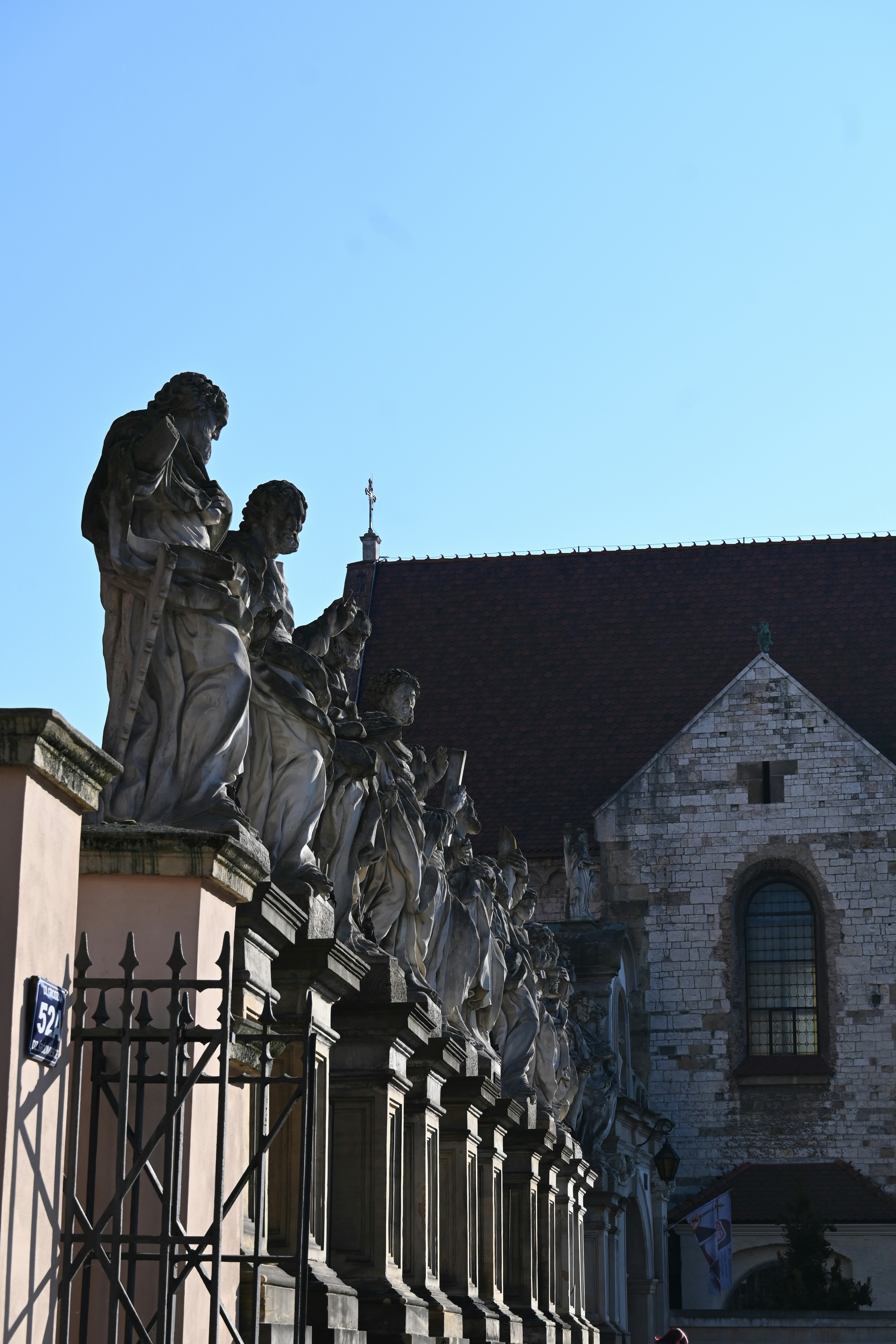 Statues adorn a building's exterior in the sunlight.