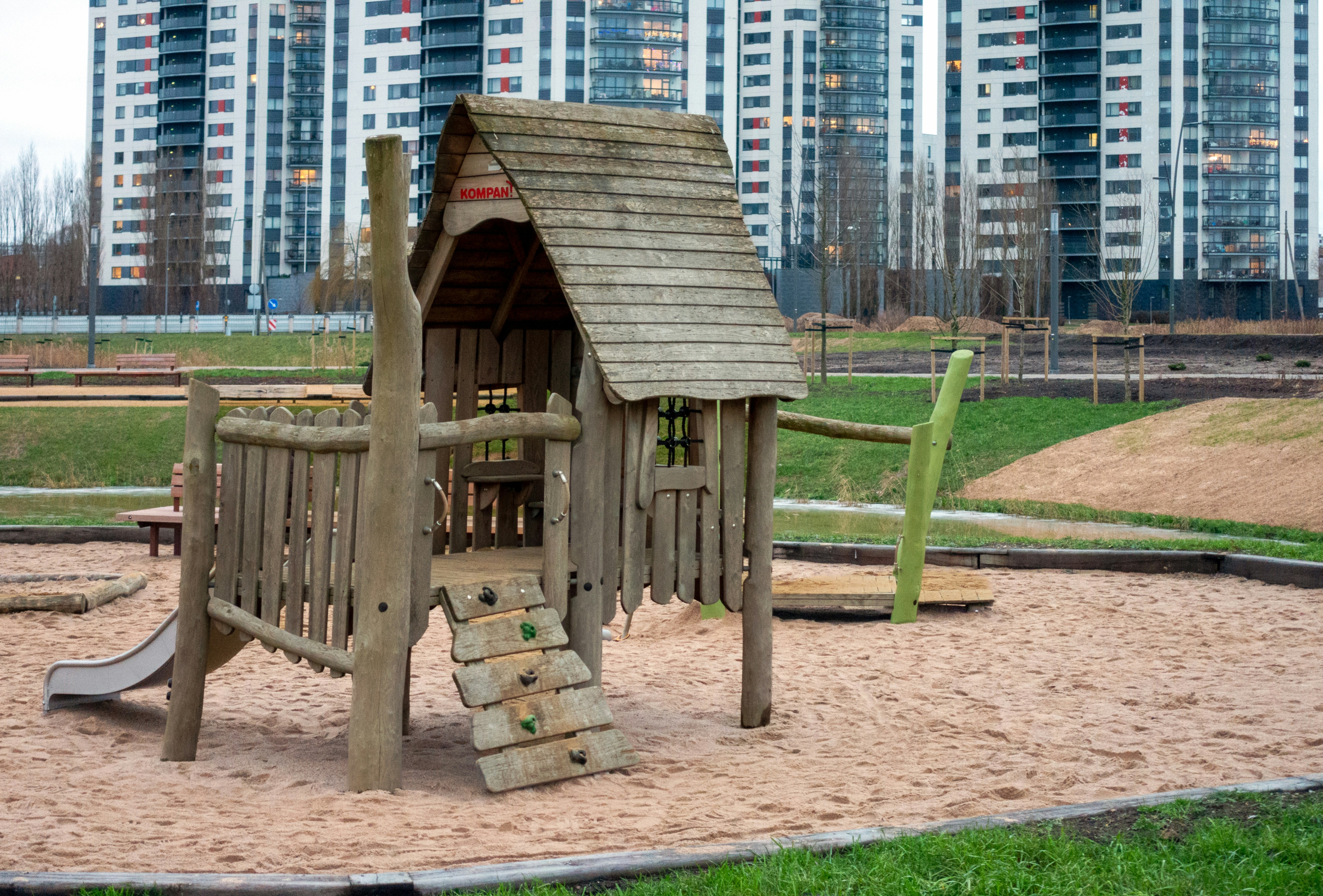 A wooden playground in front of high rise buildings.
