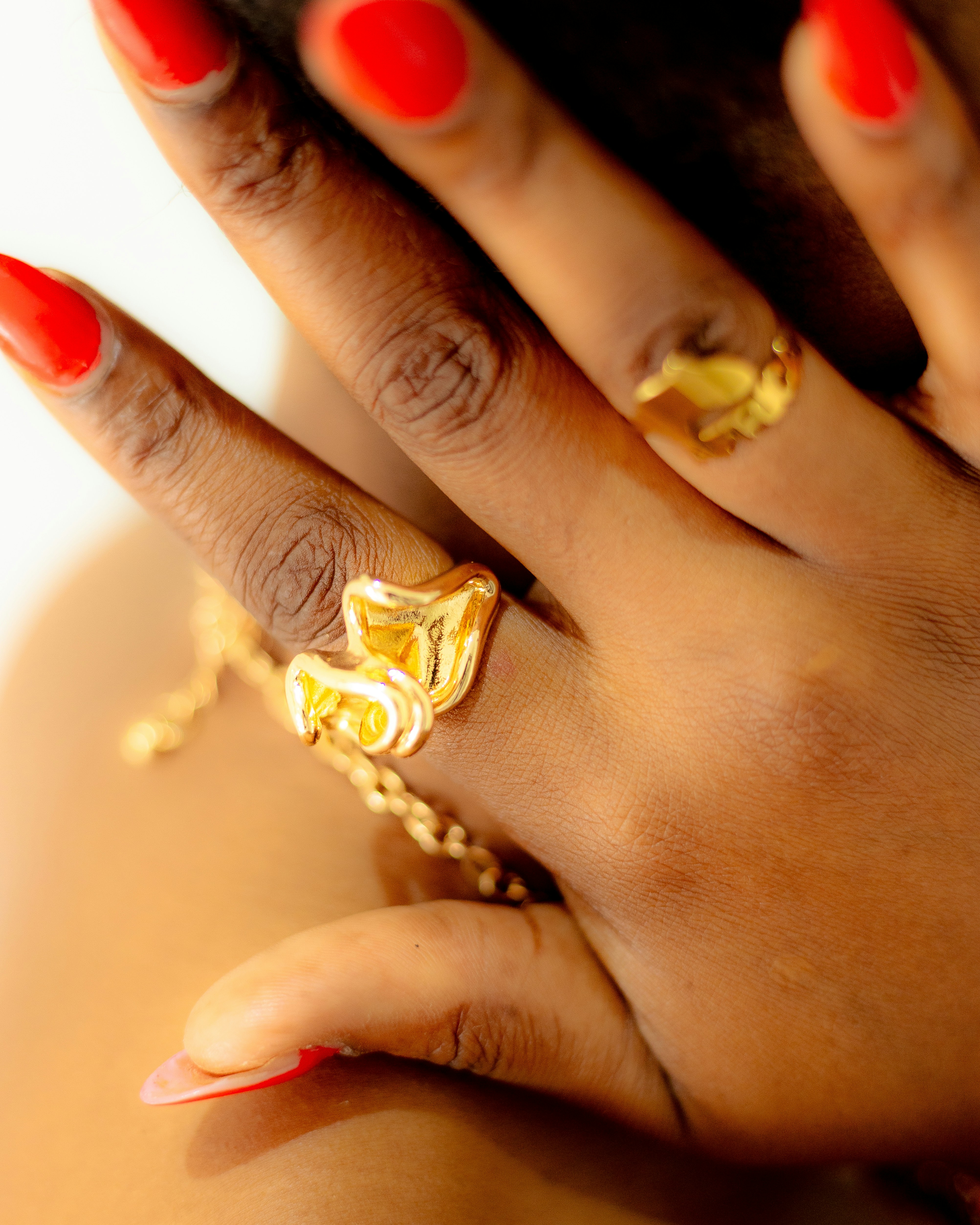 Hand with red nails and gold rings.
