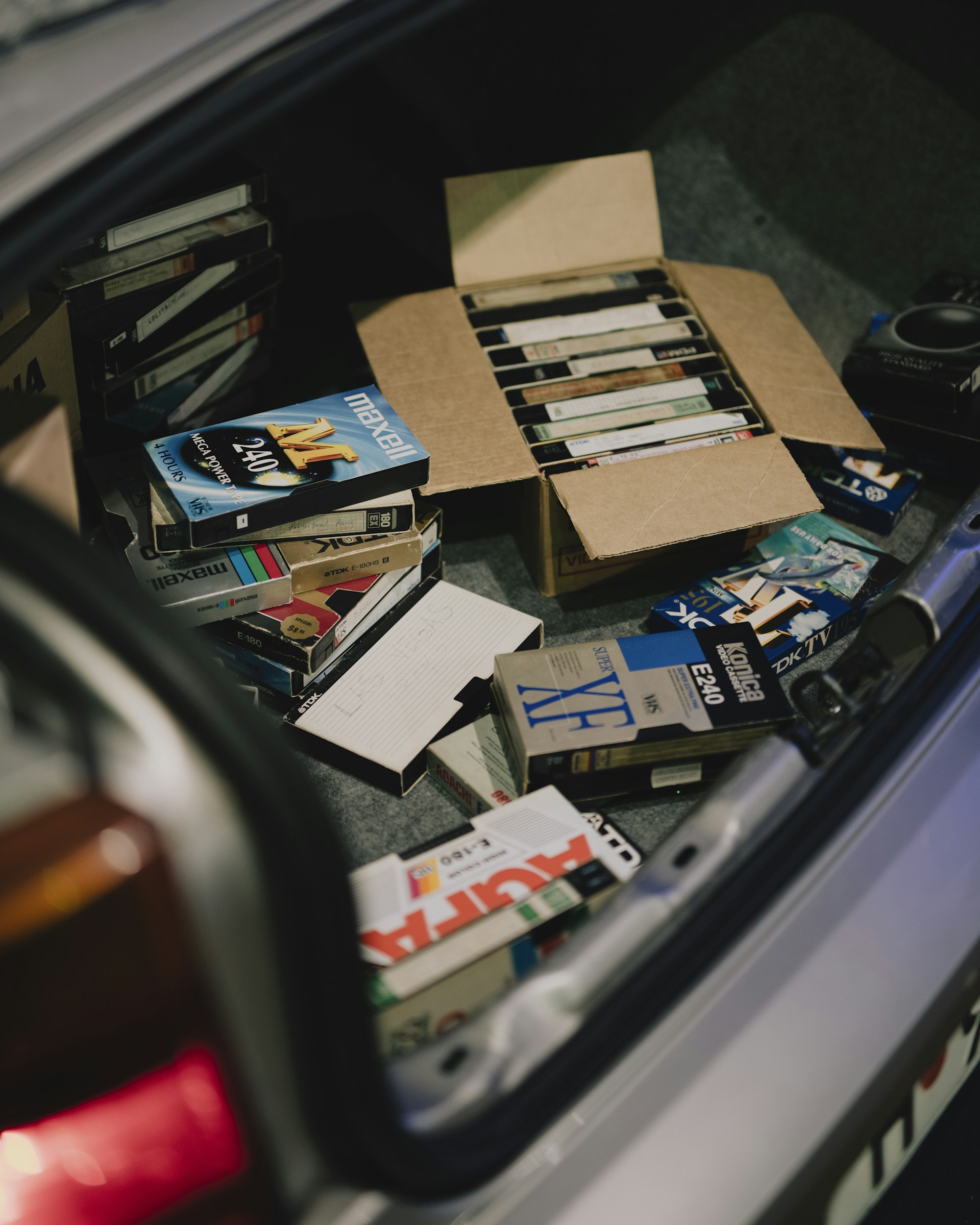 Old vhs tapes overflowing from a car trunk.