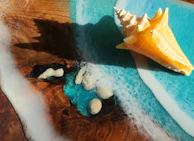 A seashell sits on a wave-like epoxy table.