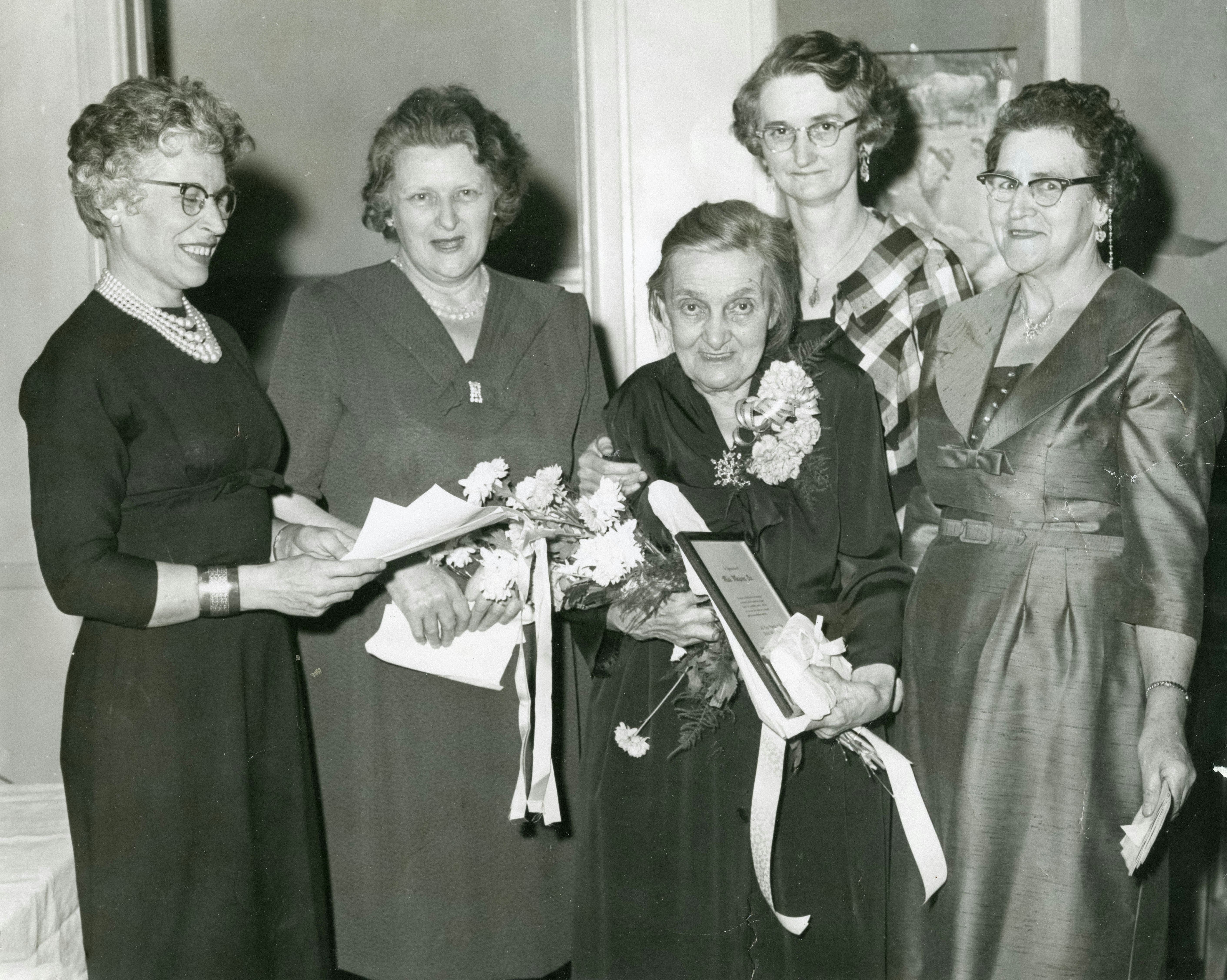 Five women posing with award and flowers