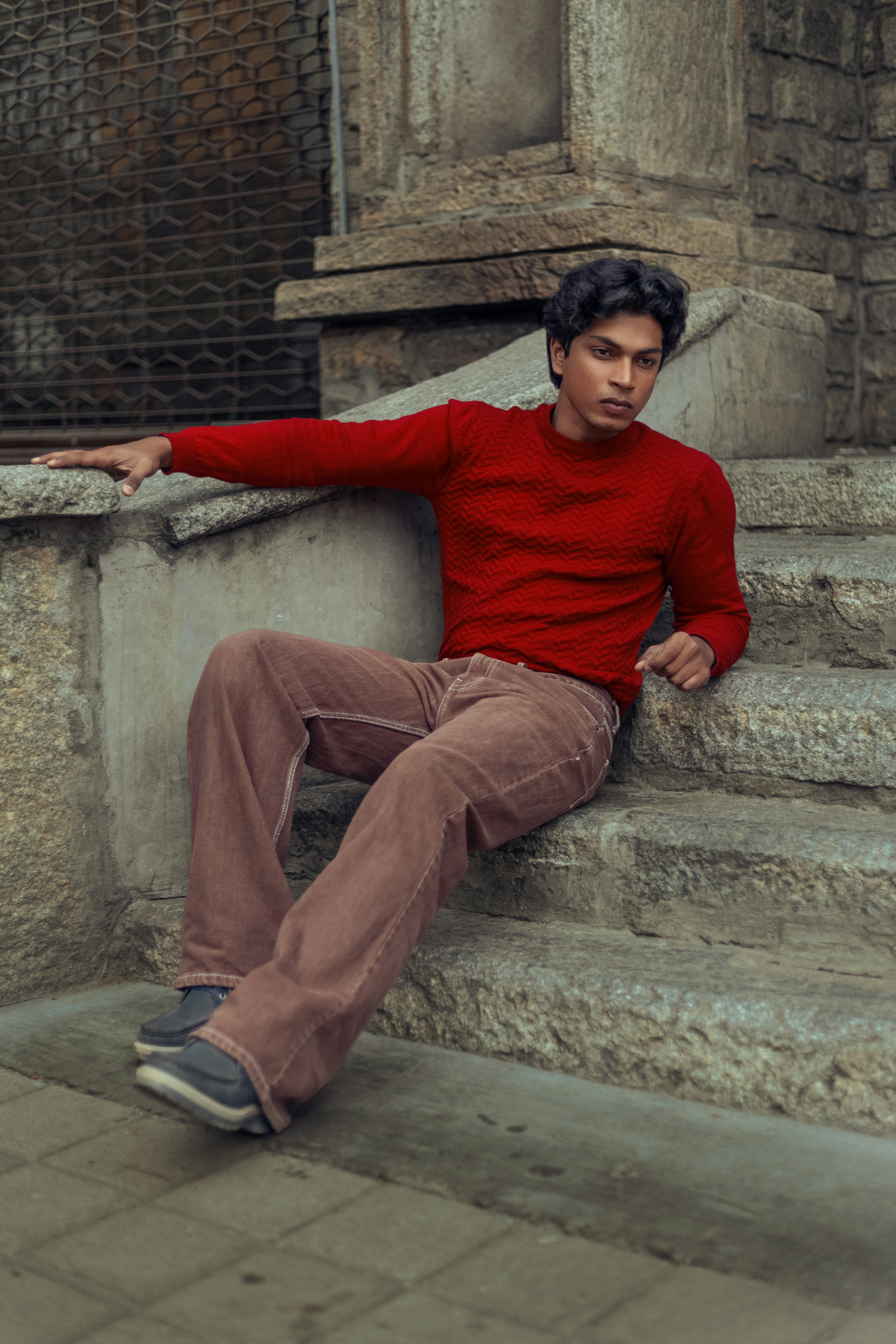 Un joven con un suéter rojo se sienta en las escaleras