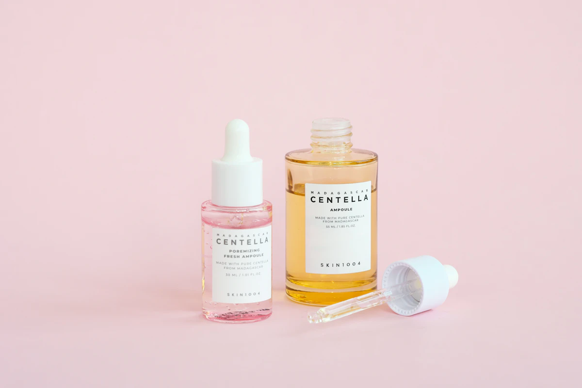 Rows of skincare serum bottles displayed against a soft pink background