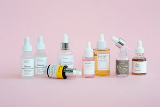 Skincare products are arranged on a pink background.