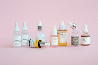 Skincare products are arranged on a pink background.