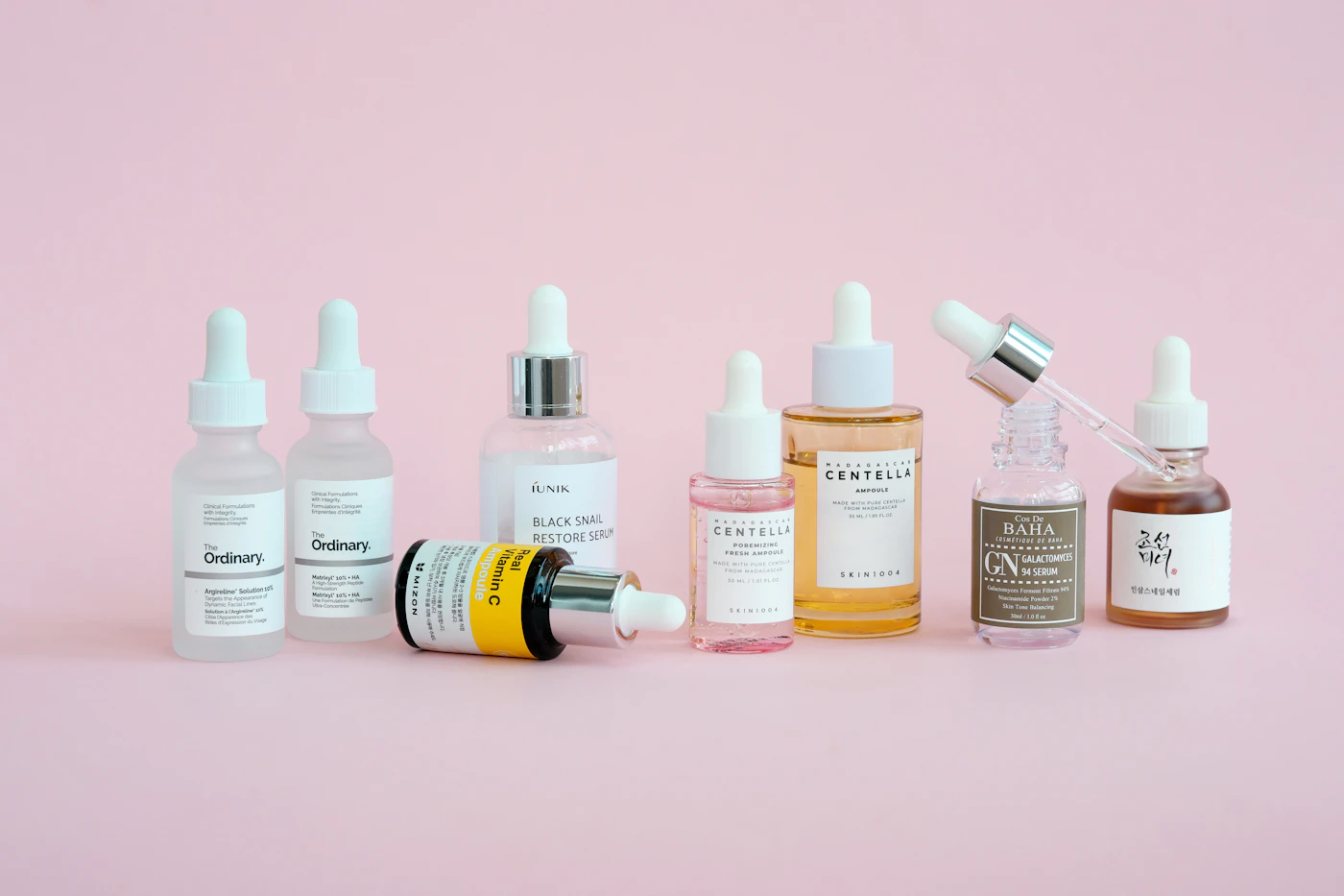 Skincare bottles arranged on a soft pink background