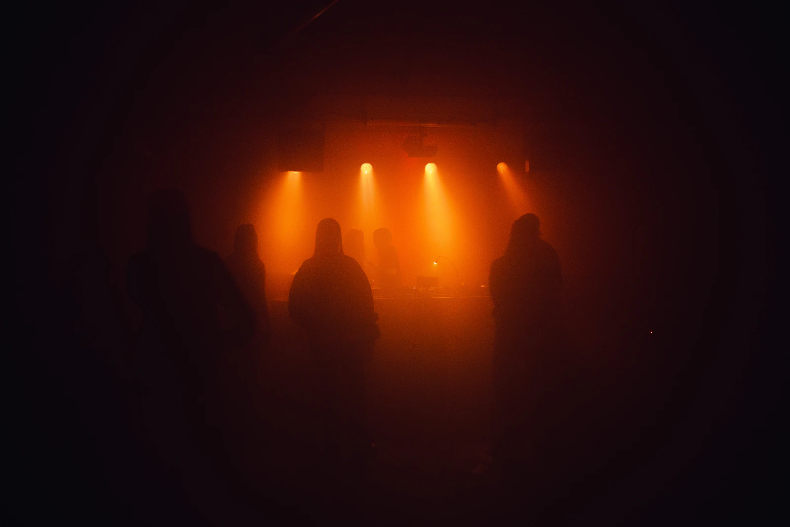 Orange stage spotlights cutting through darkness at a live show