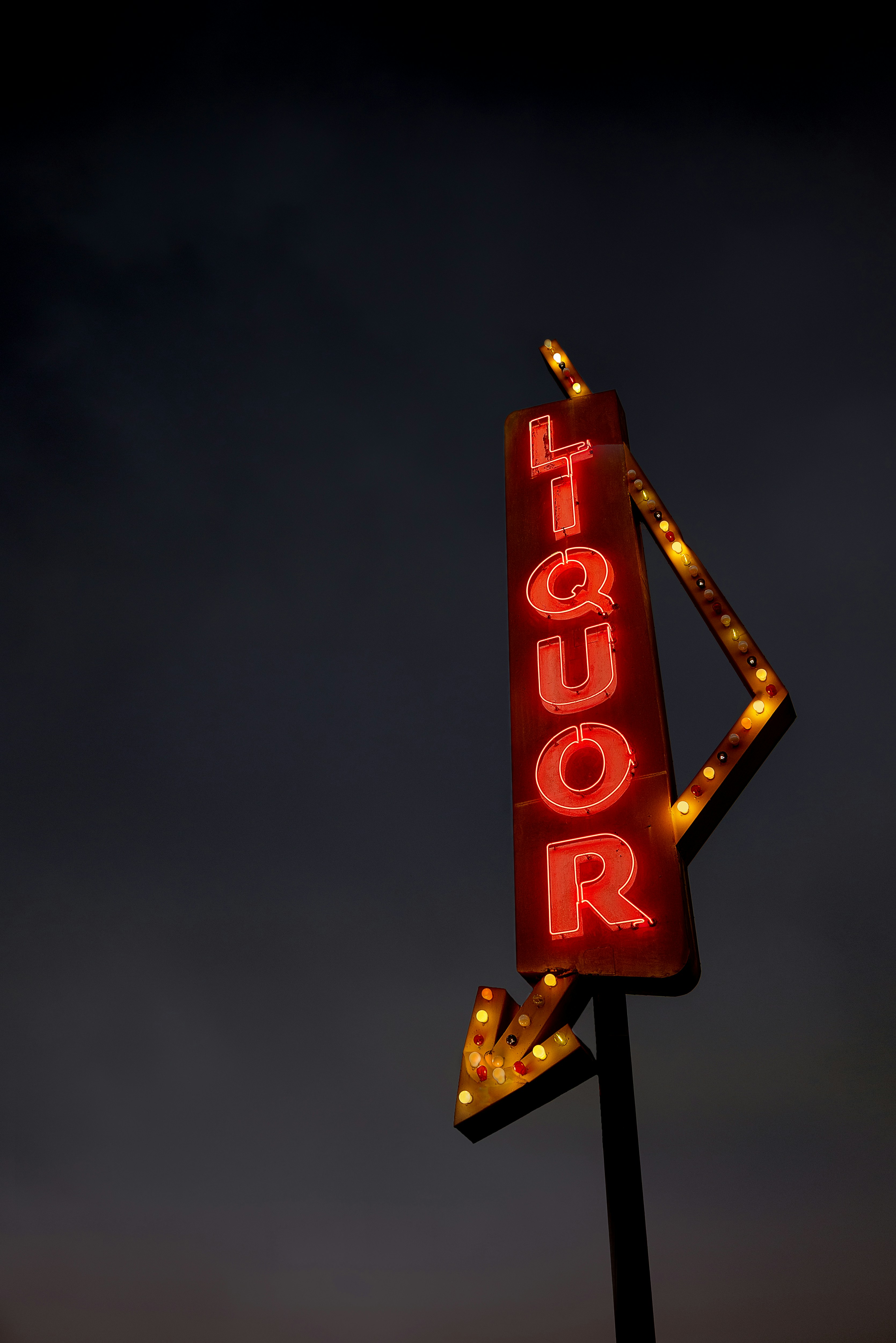 A red neon liquor sign points downward.