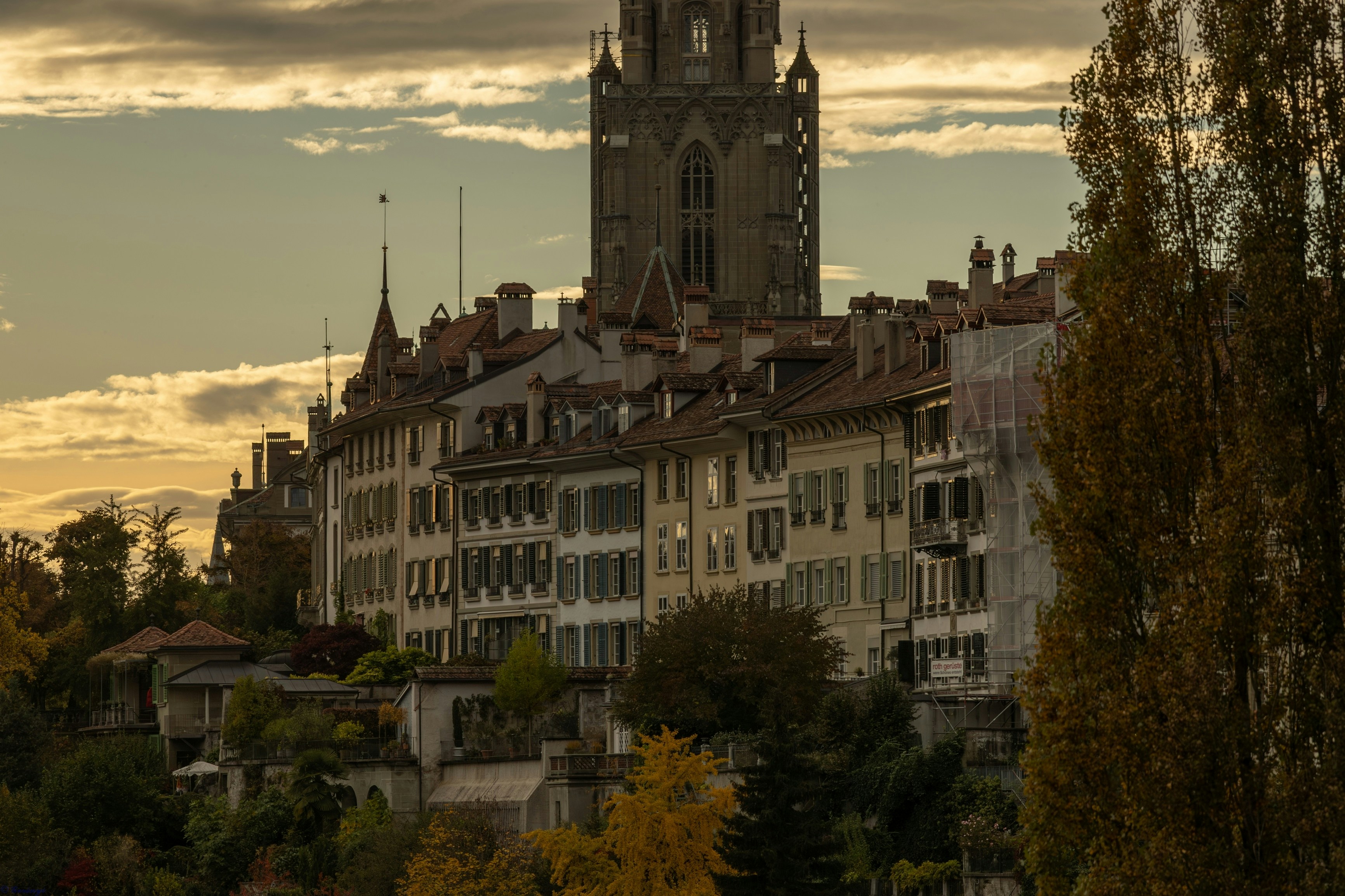 Cityscape with buildings and church tower at sunset.