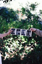 Parents hold up sonogram photos, announcing a baby.