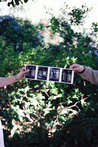 Parents hold up sonogram photos, announcing a baby.