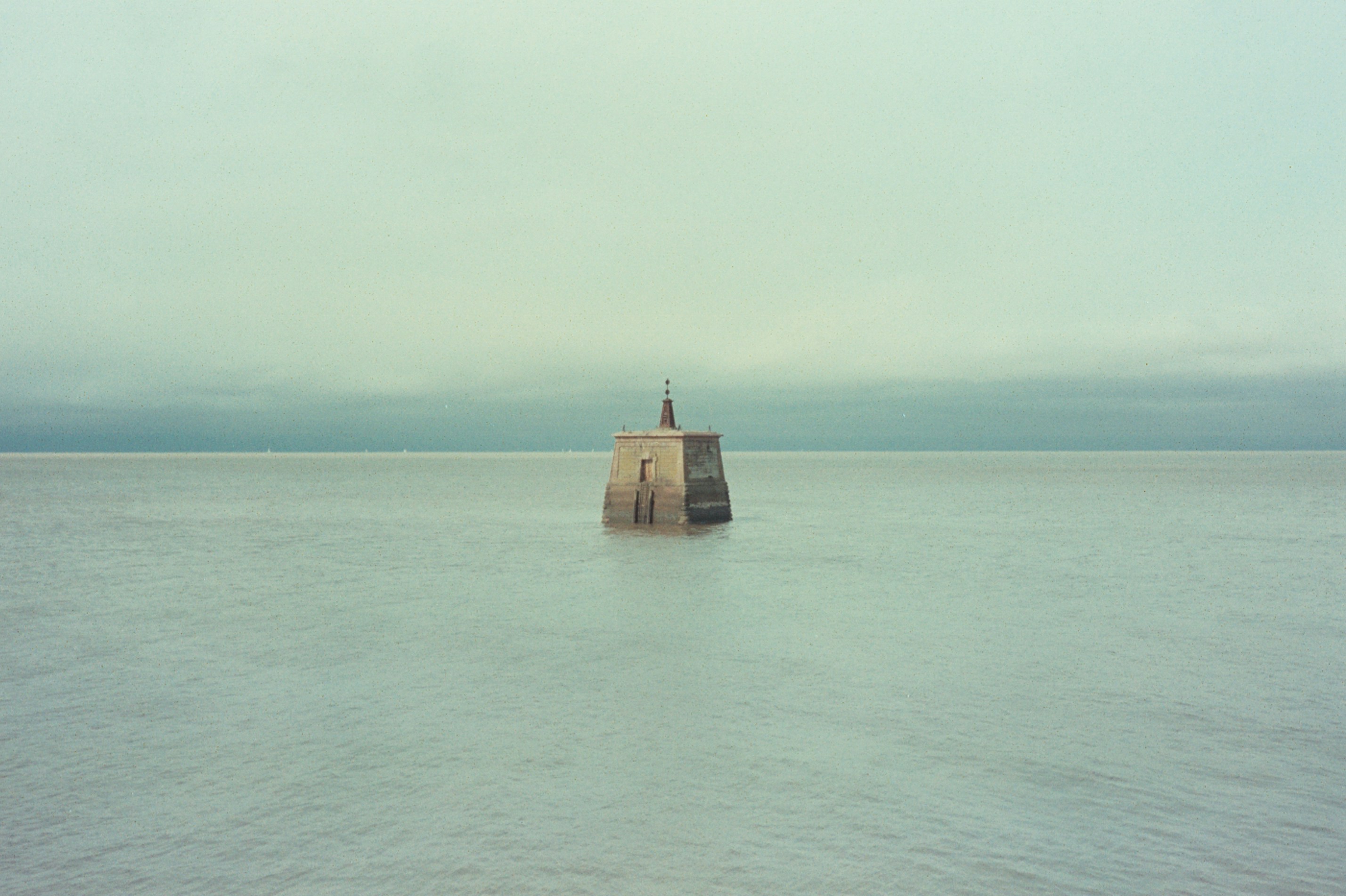 A solitary beacon stands in the sea.