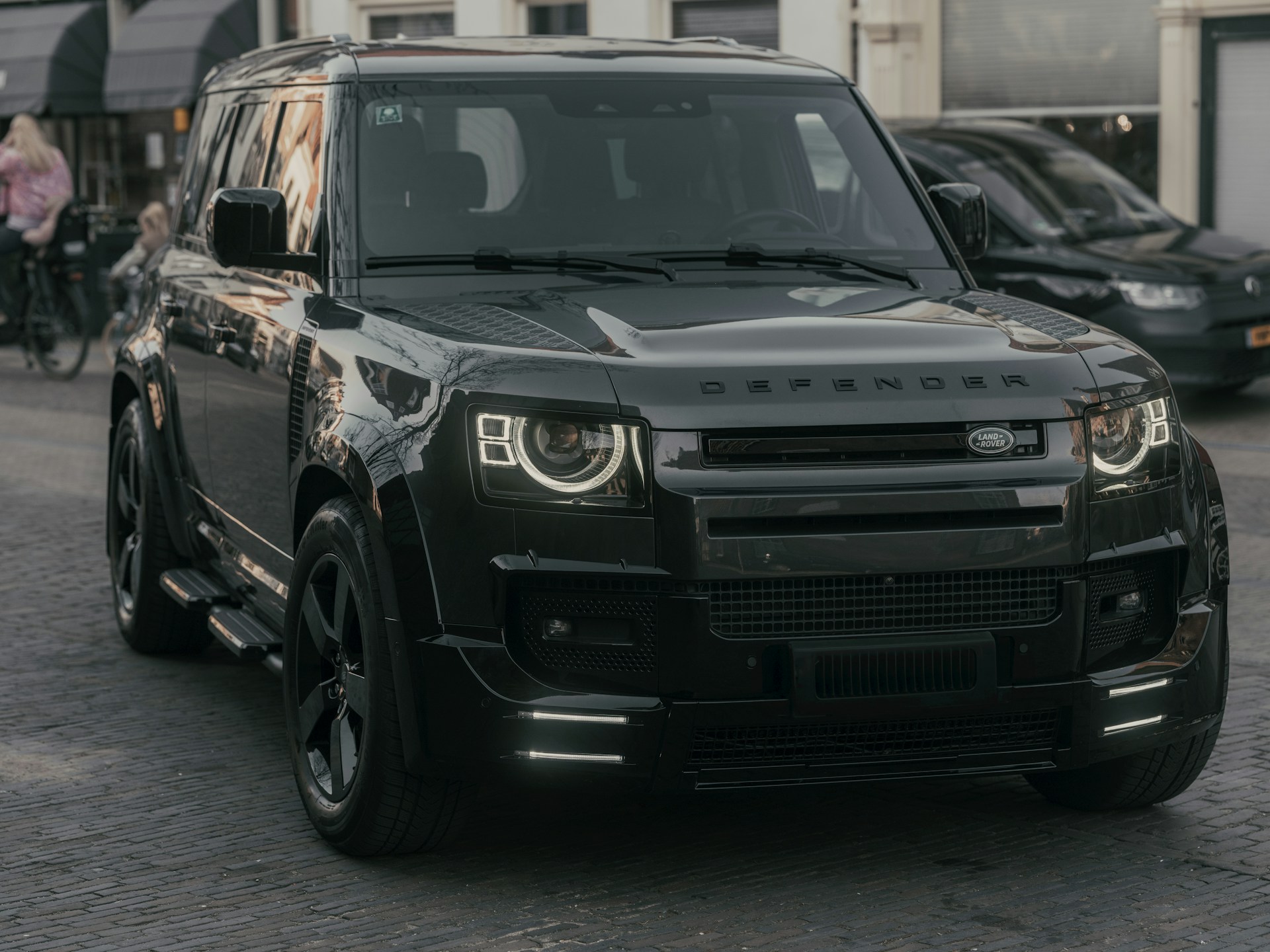 A black land rover defender is parked.