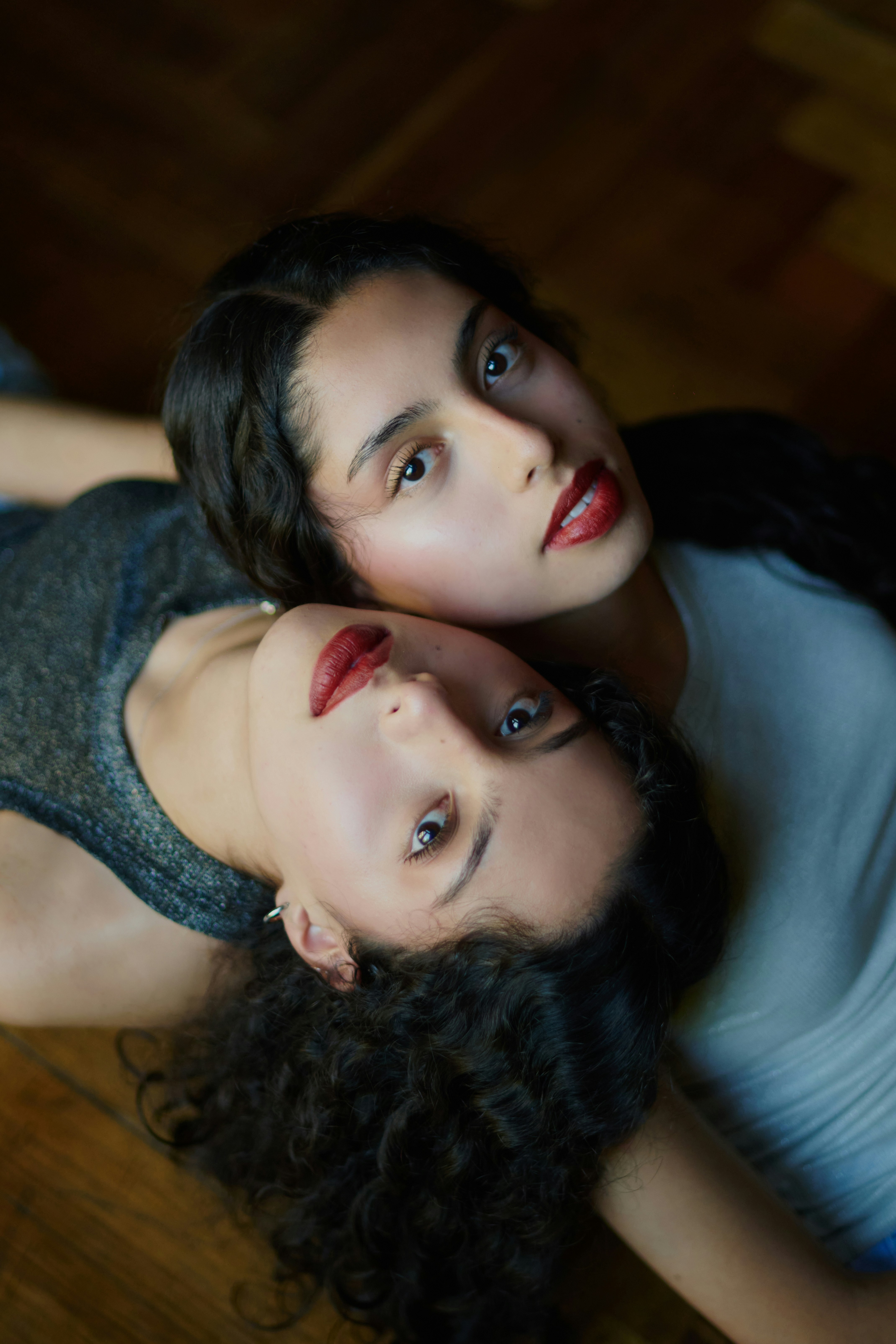 Two women lie together, looking at the camera.