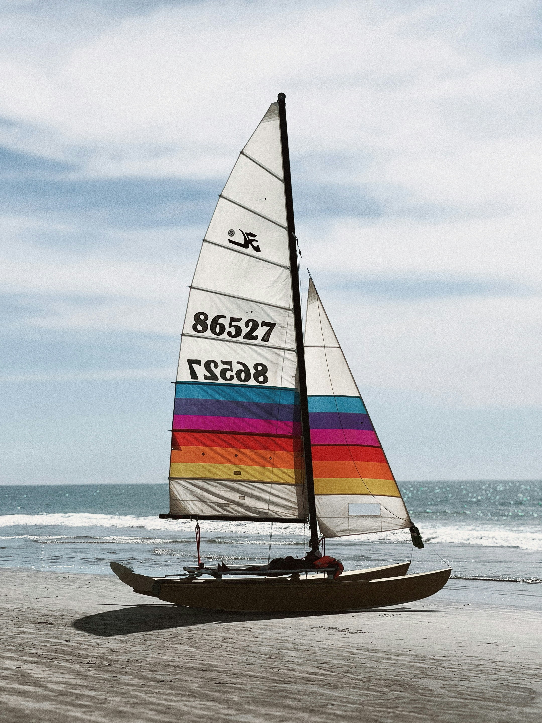 Sailboat sits on the beach near the ocean.