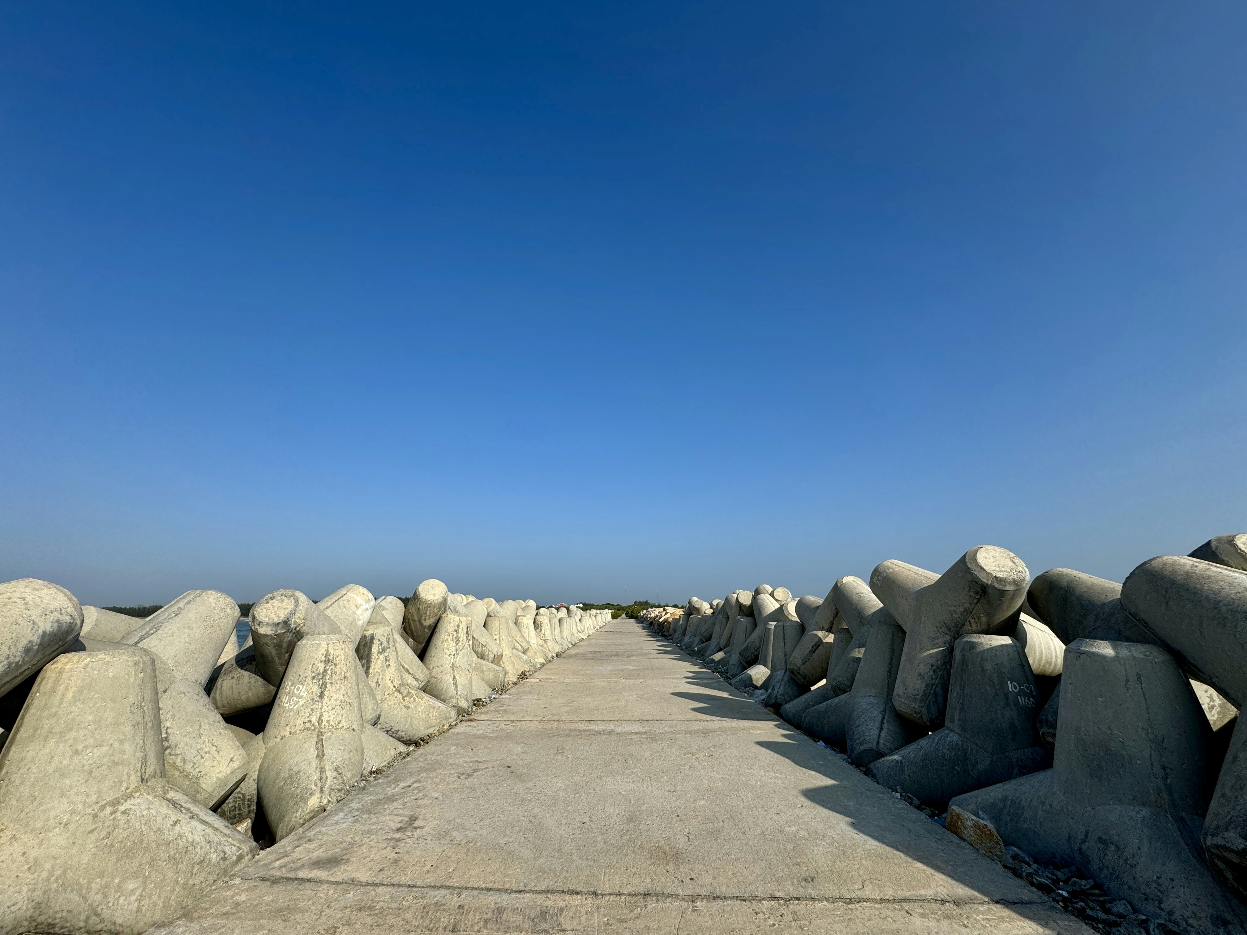 Concrete tetrapods line a walkway under a blue sky.