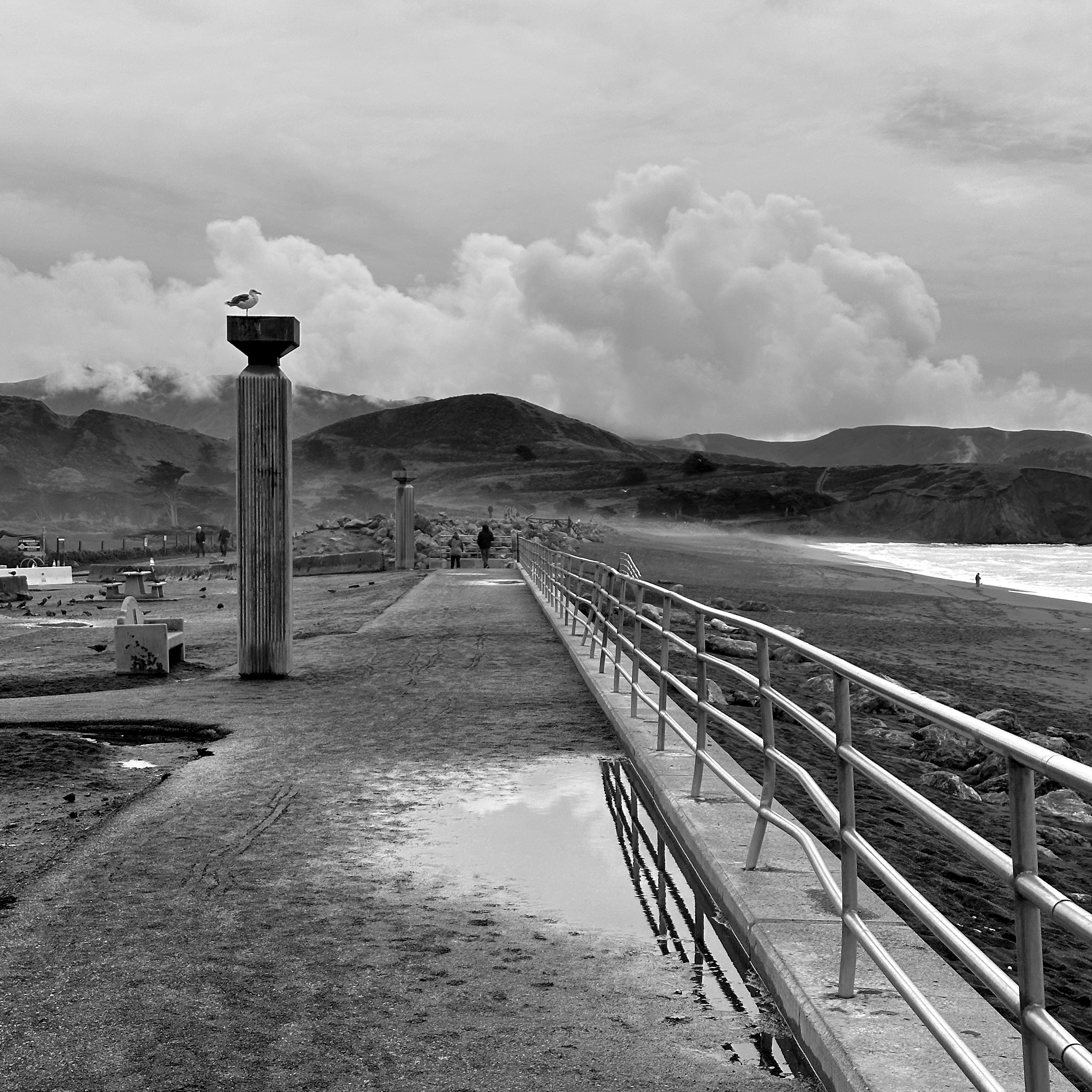 曇り空の下、地平線に向かって桟橋が伸びています。
