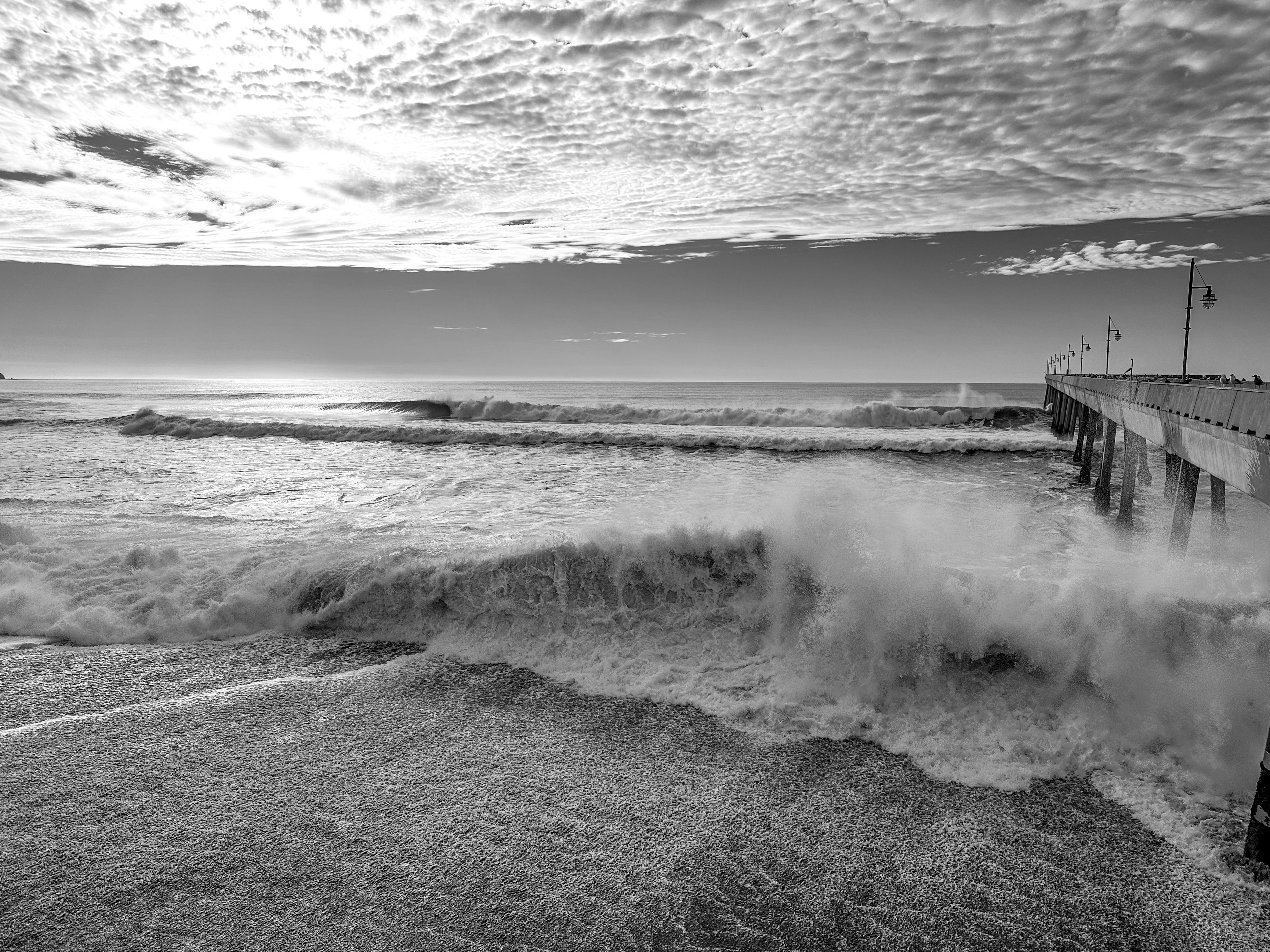 桟橋近くの海岸に波が打ち寄せる。