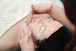 Woman enjoying a facial massage with closed eyes.