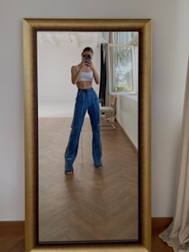 Woman takes a mirror selfie wearing stylish outfit.