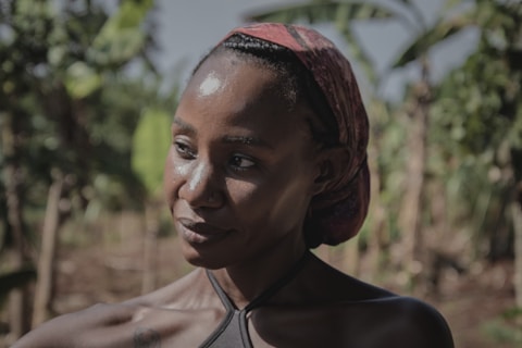 A woman with a headscarf stands outdoors.