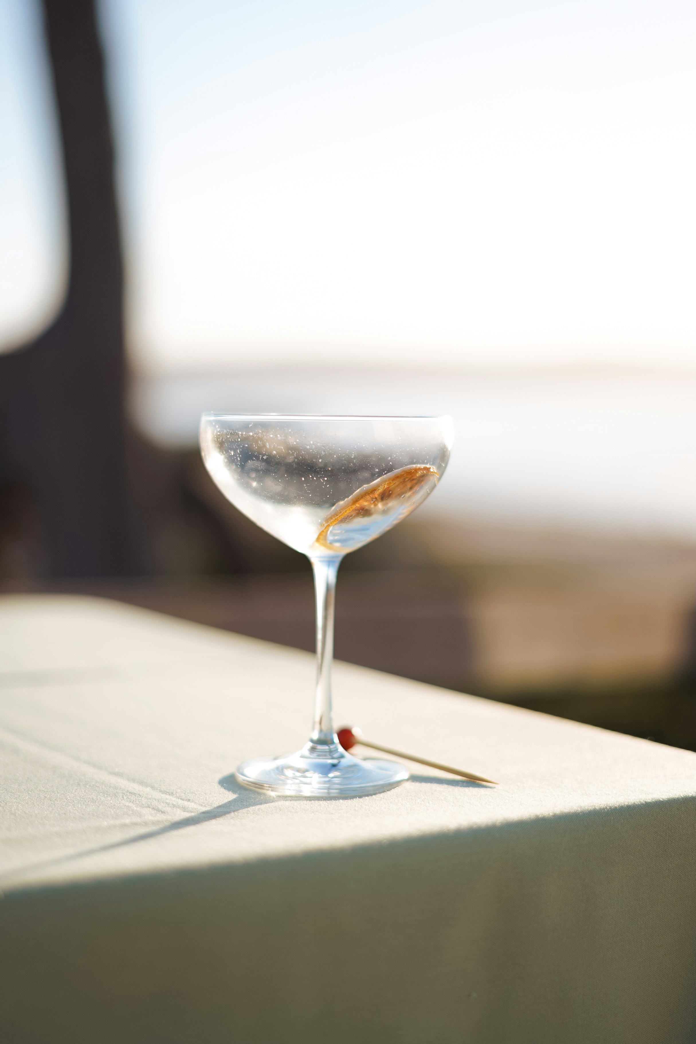 A martini cocktail sits on a table outdoors.