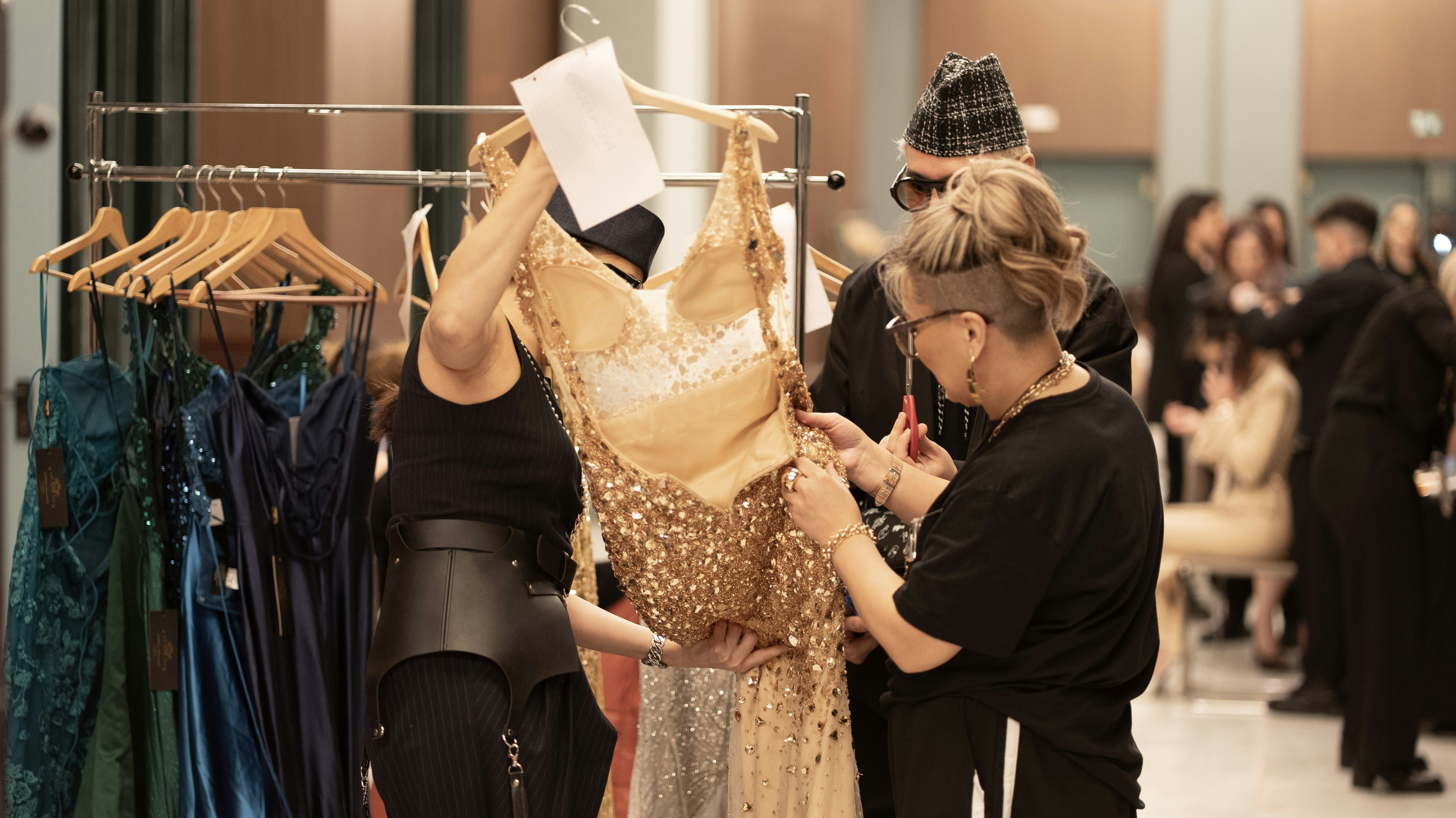 Stylists are preparing a gown for a fashion show.