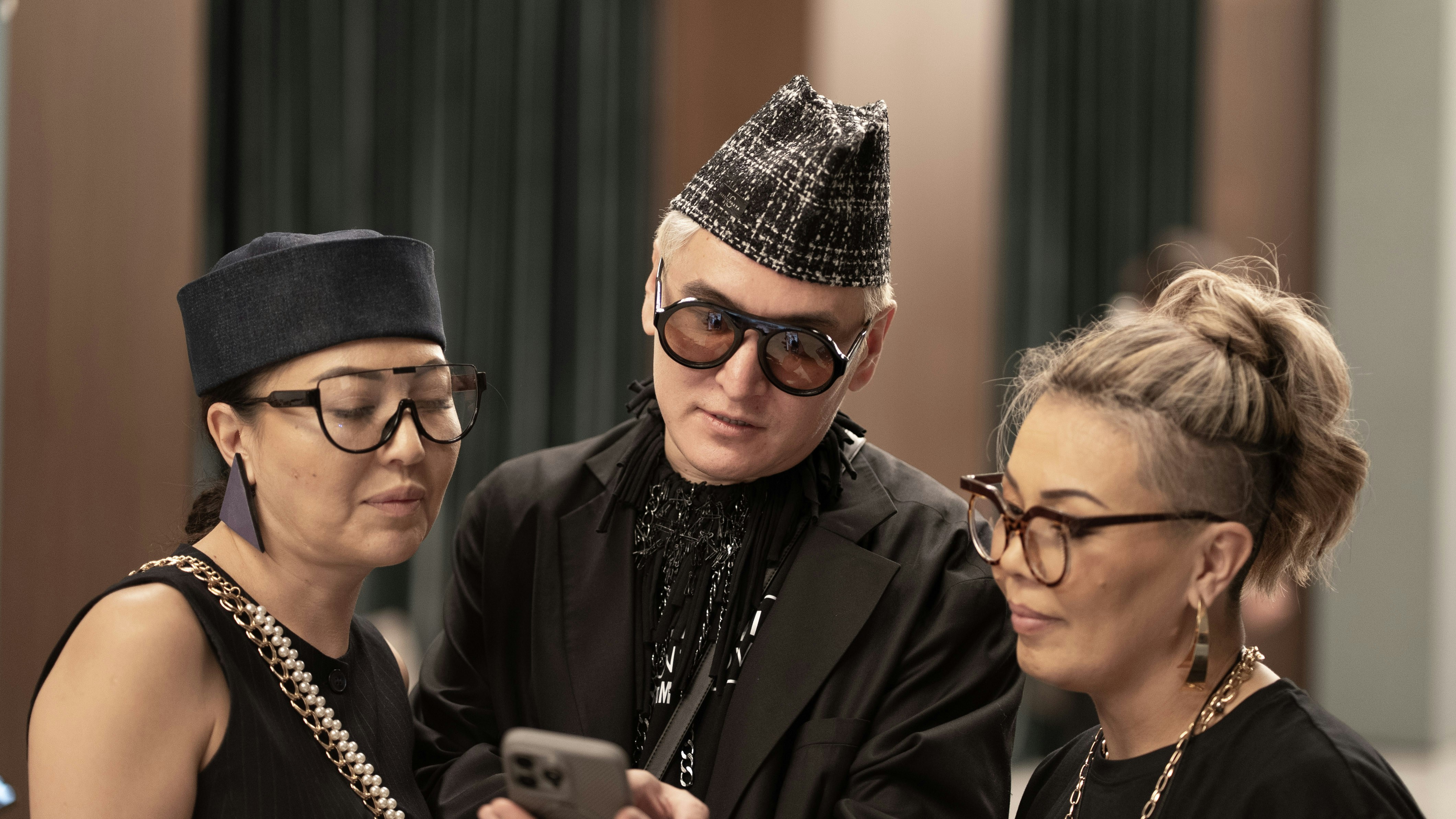 Three people are looking at a phone together.