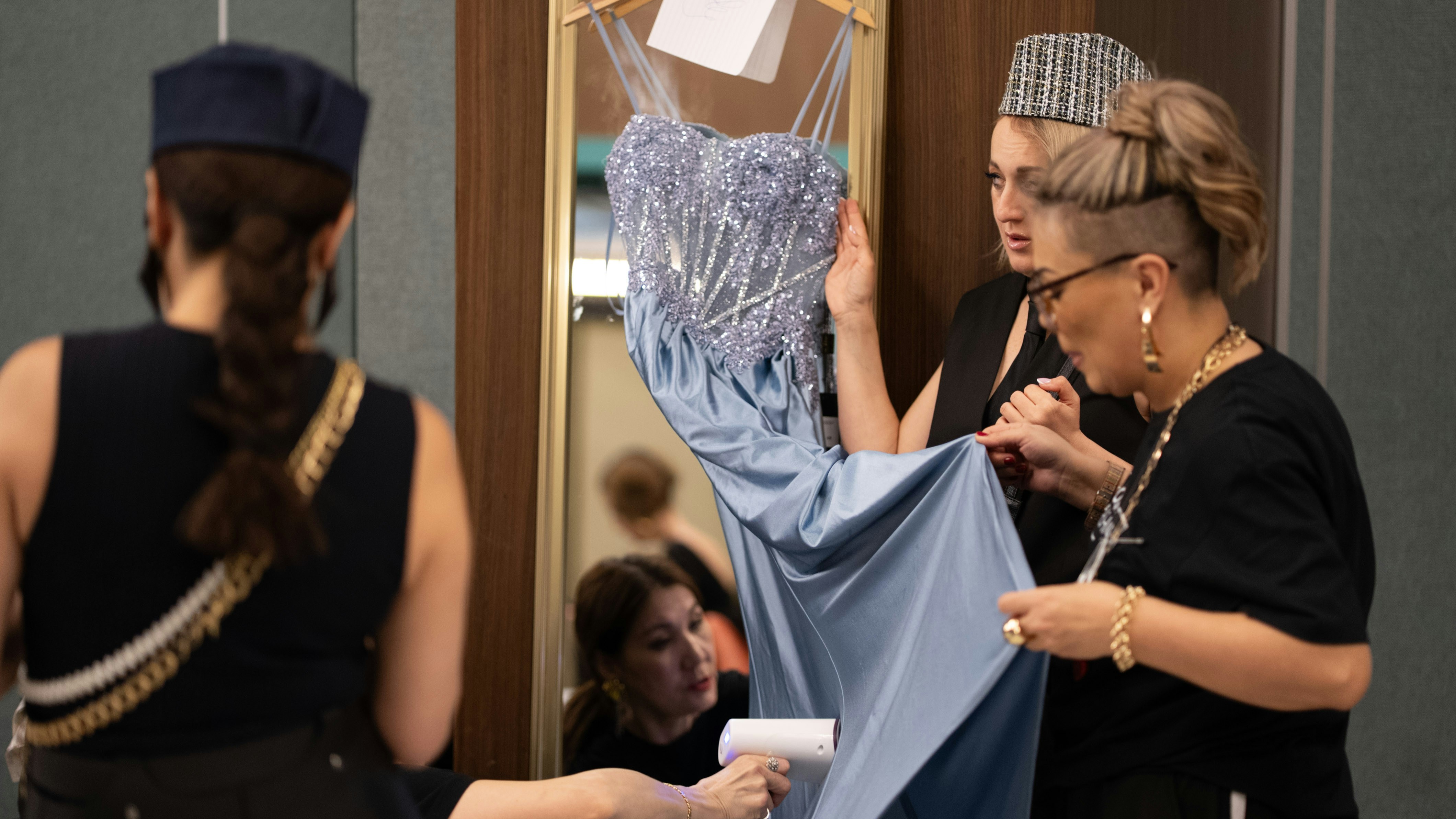 Fashion designers adjusting blue dress