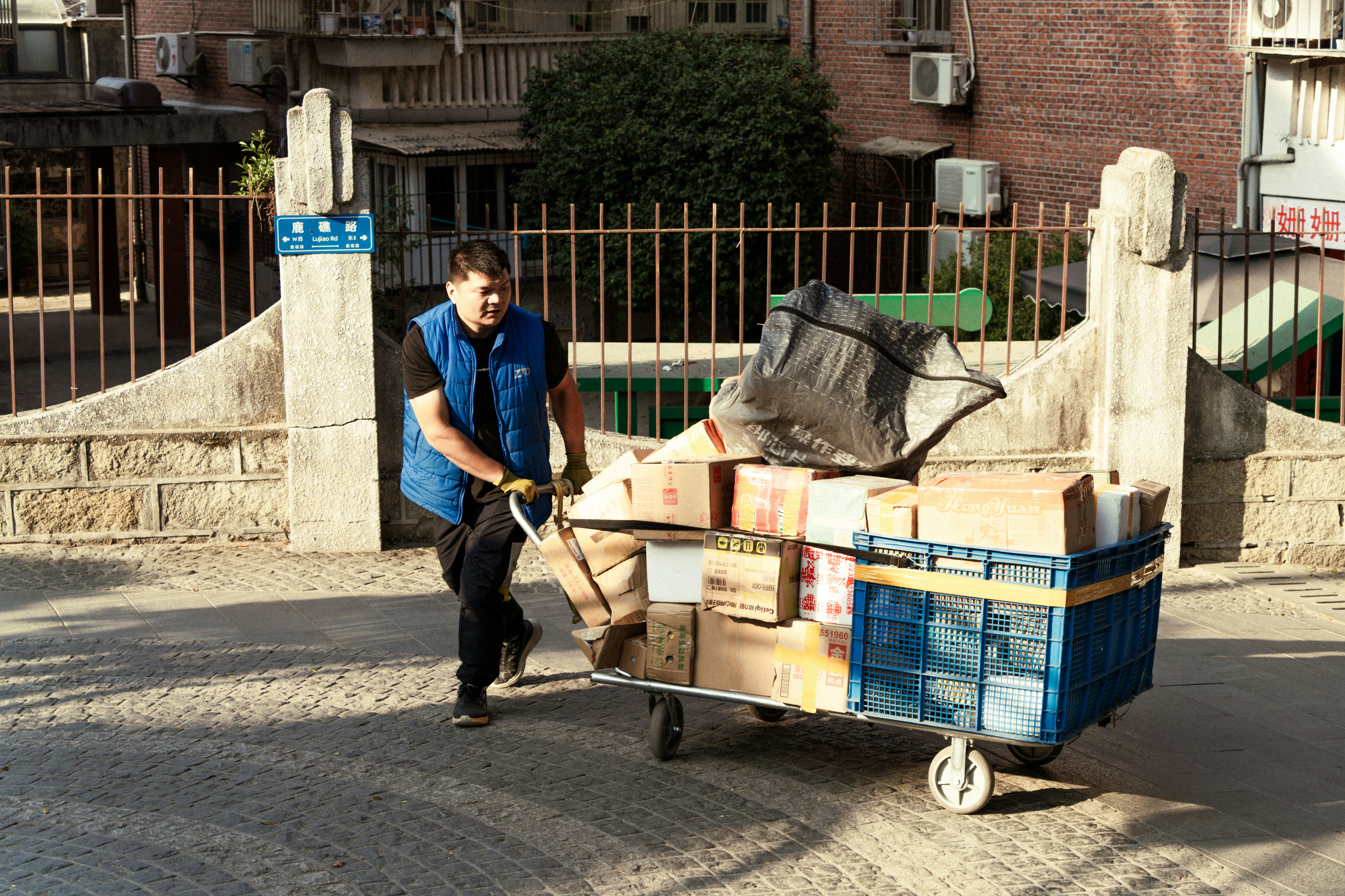 Man pushes a cart filled with packages and trash.