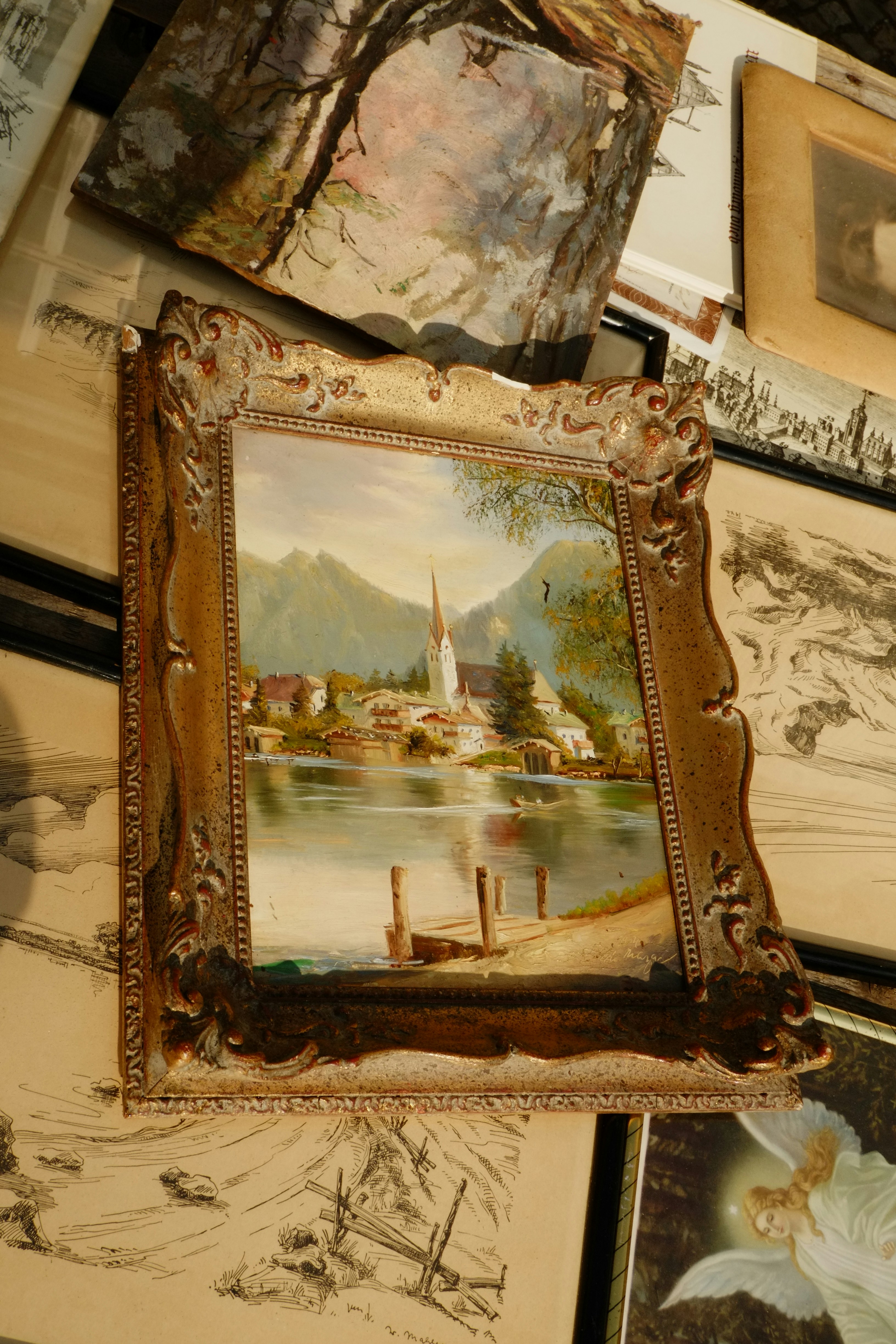 A landscape painting with a church in a decorative frame.