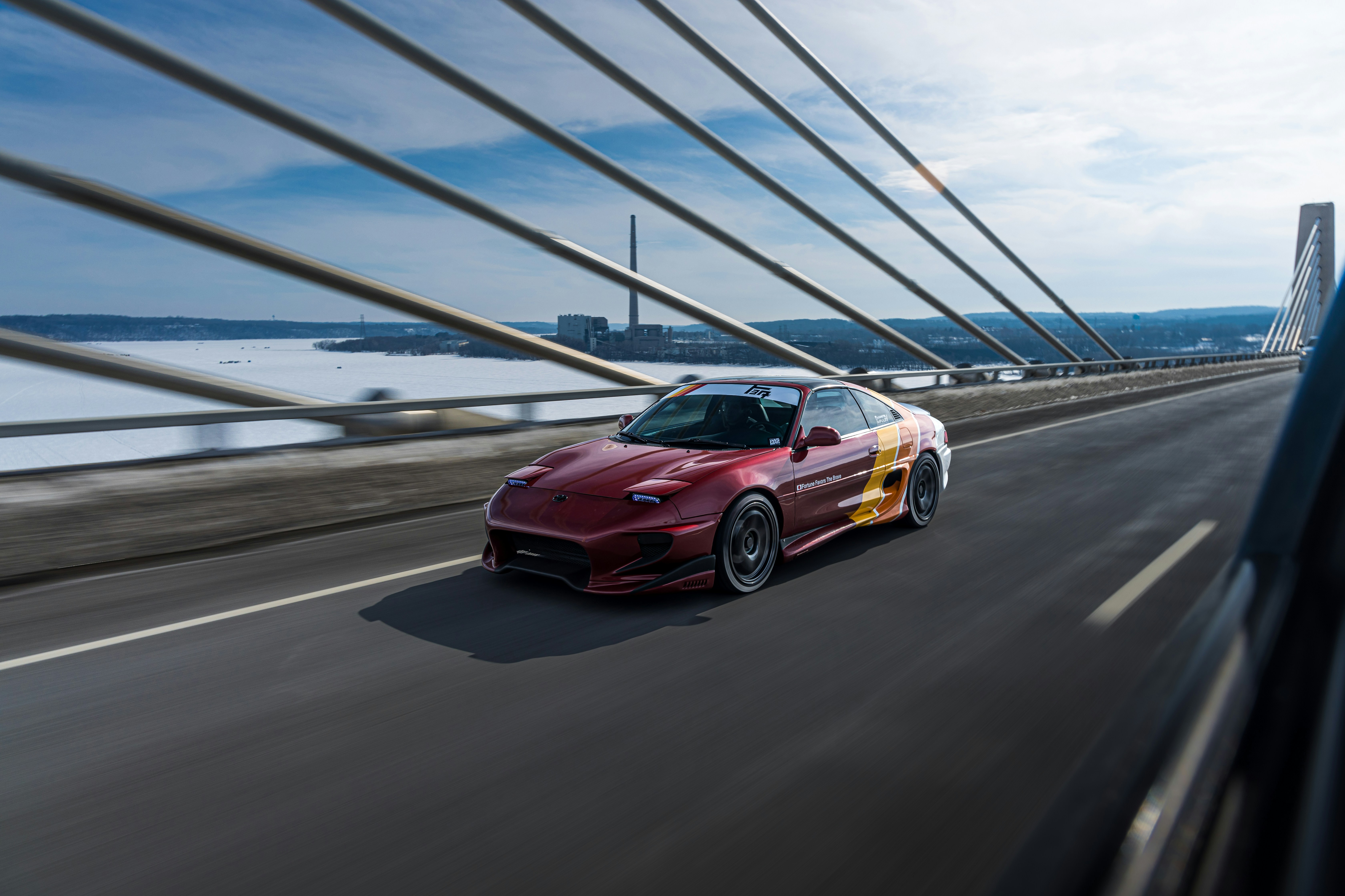 A sports car speeds across a bridge.