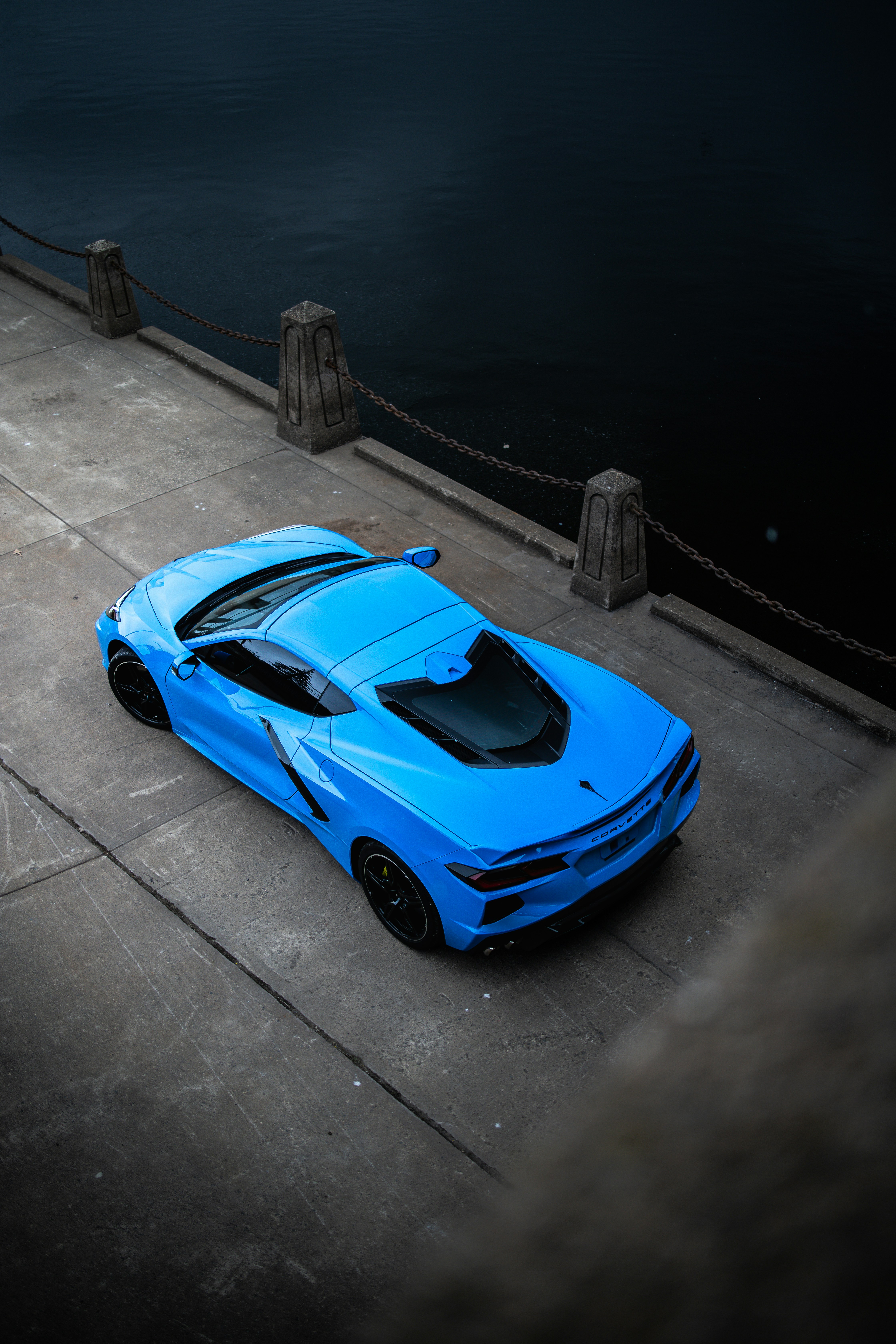 A bright blue sports car parked near water.