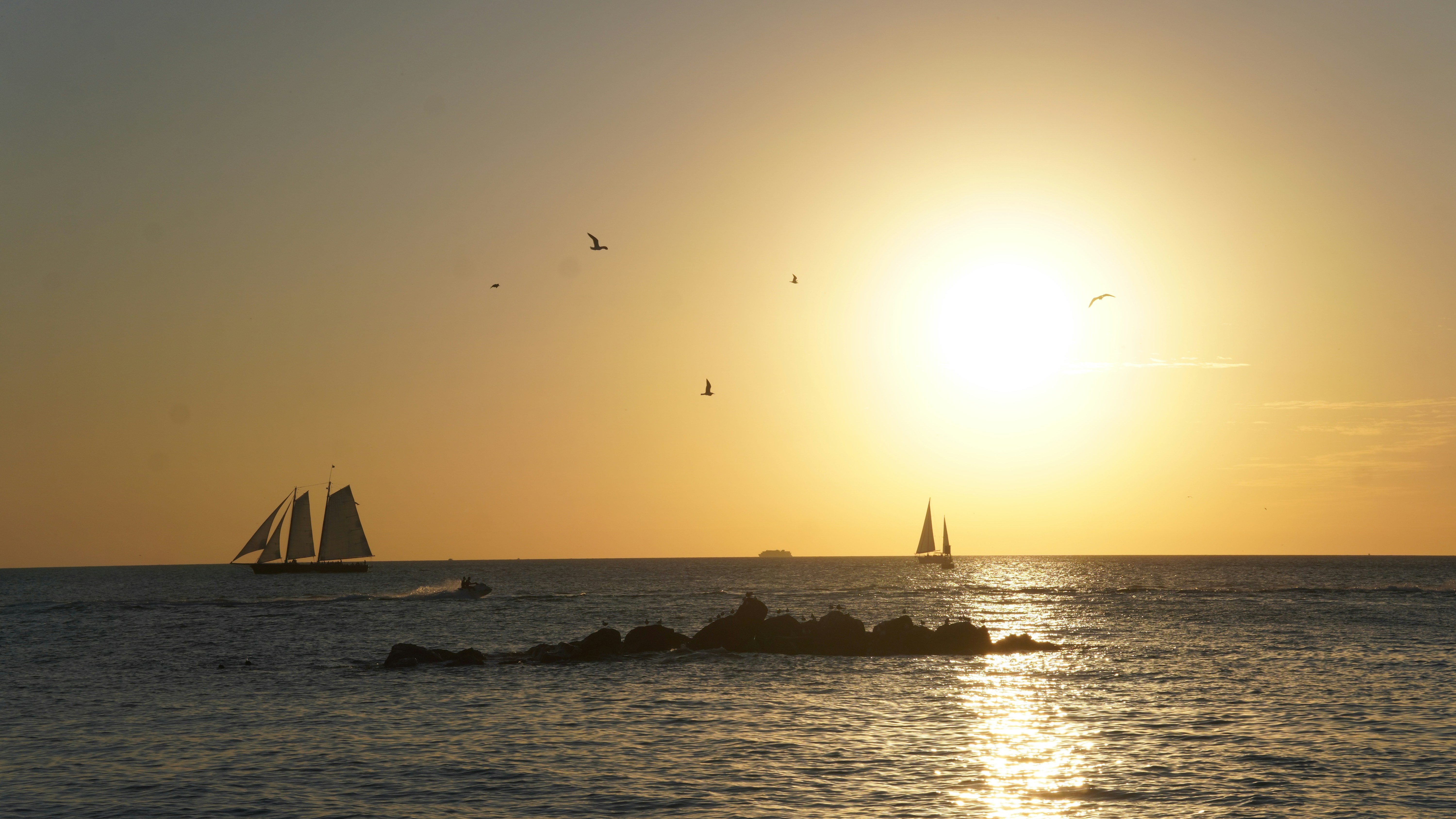 Sailboats cruise during a beautiful sunset.