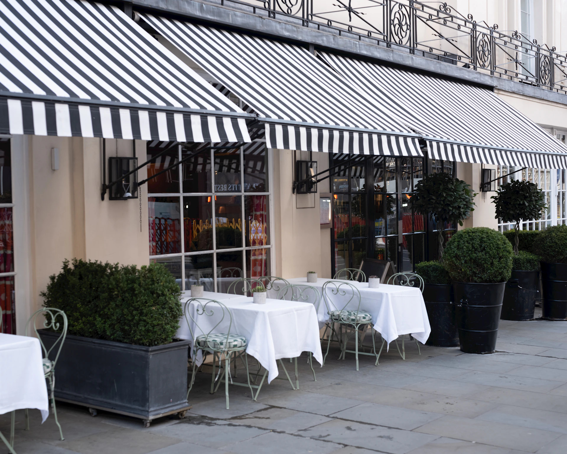 Outdoor cafe with striped awnings and tables.
