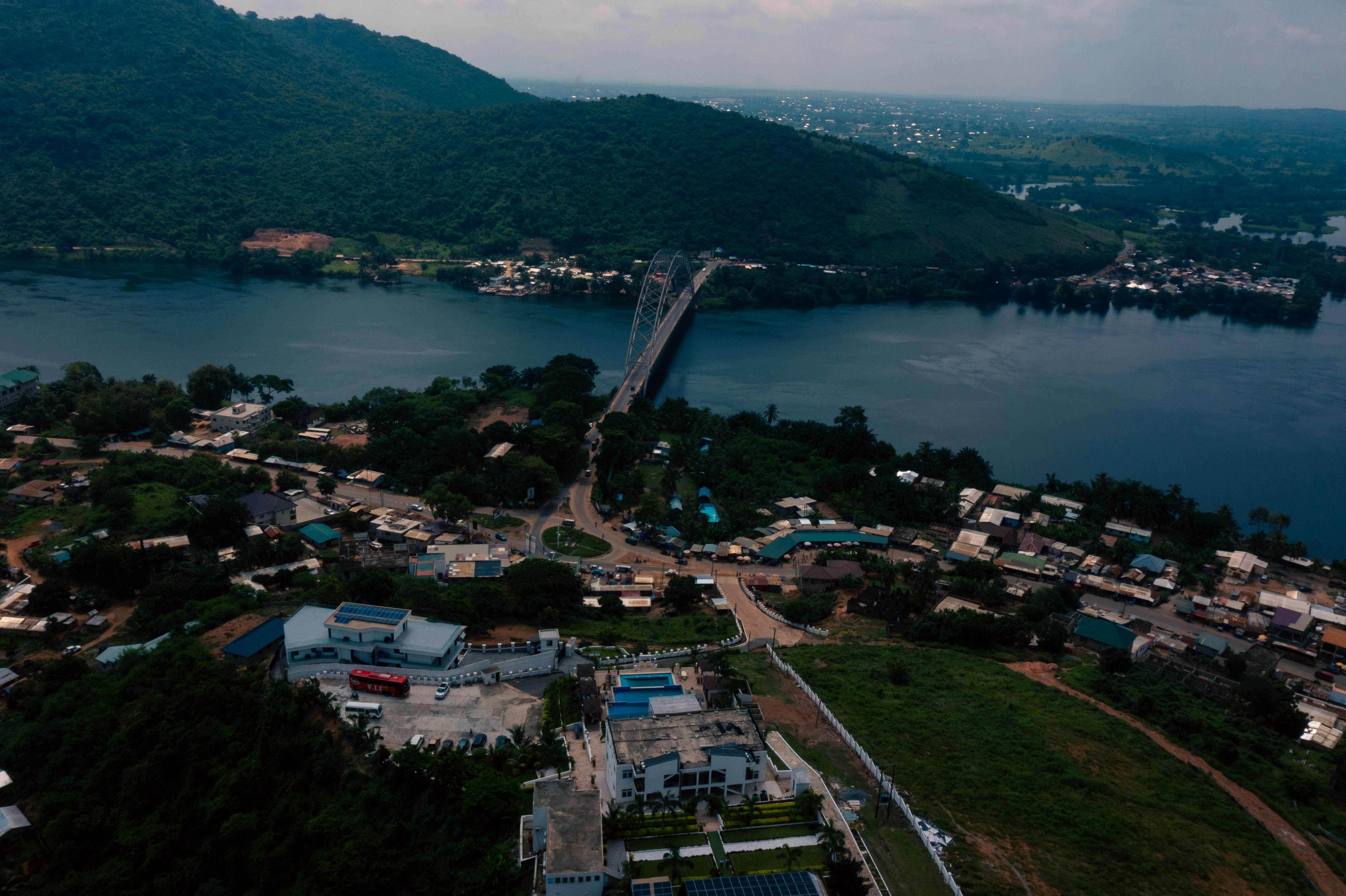 A bridge connects a town and a forested hill.