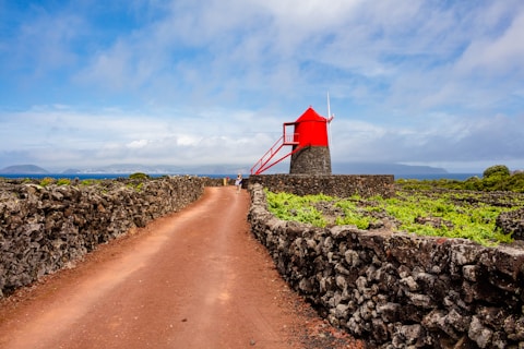 A red windmill stands amidst a beautiful landscape.