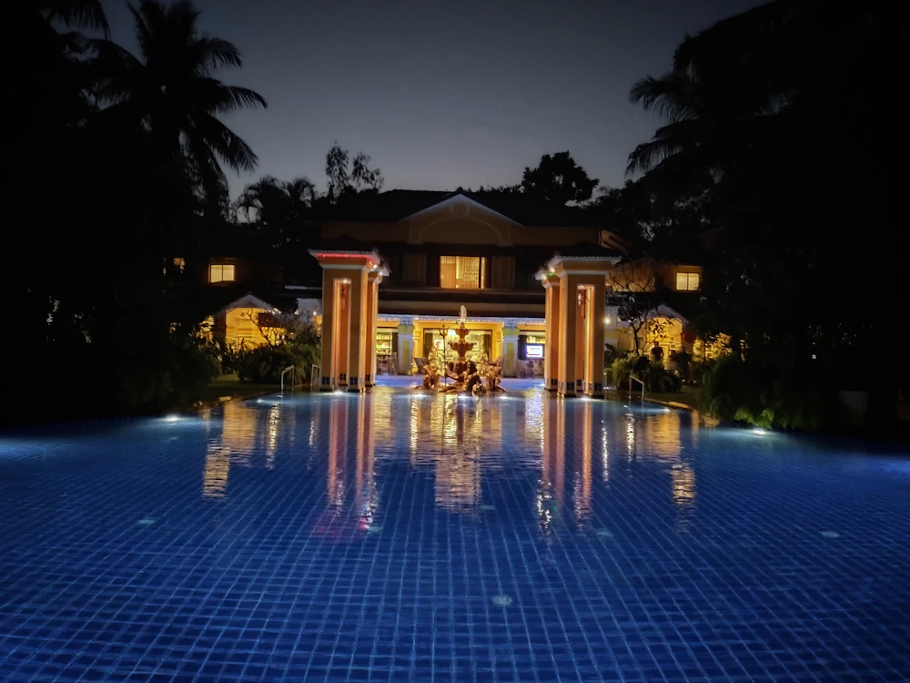 Lit pool reflecting a home at night