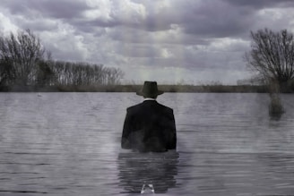 Man stands in water under a cloudy sky.