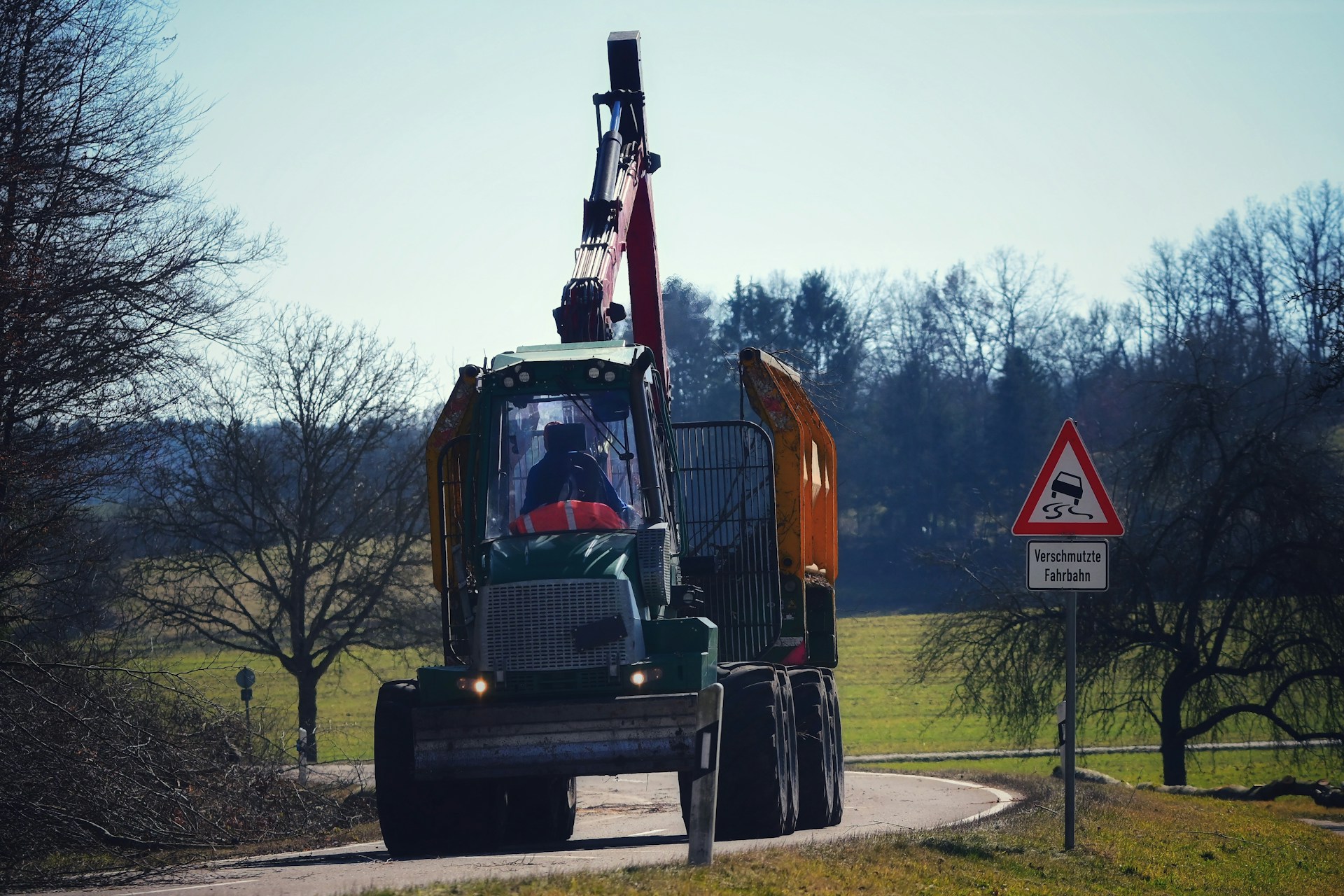 A forestry machine is operating on a rural road.